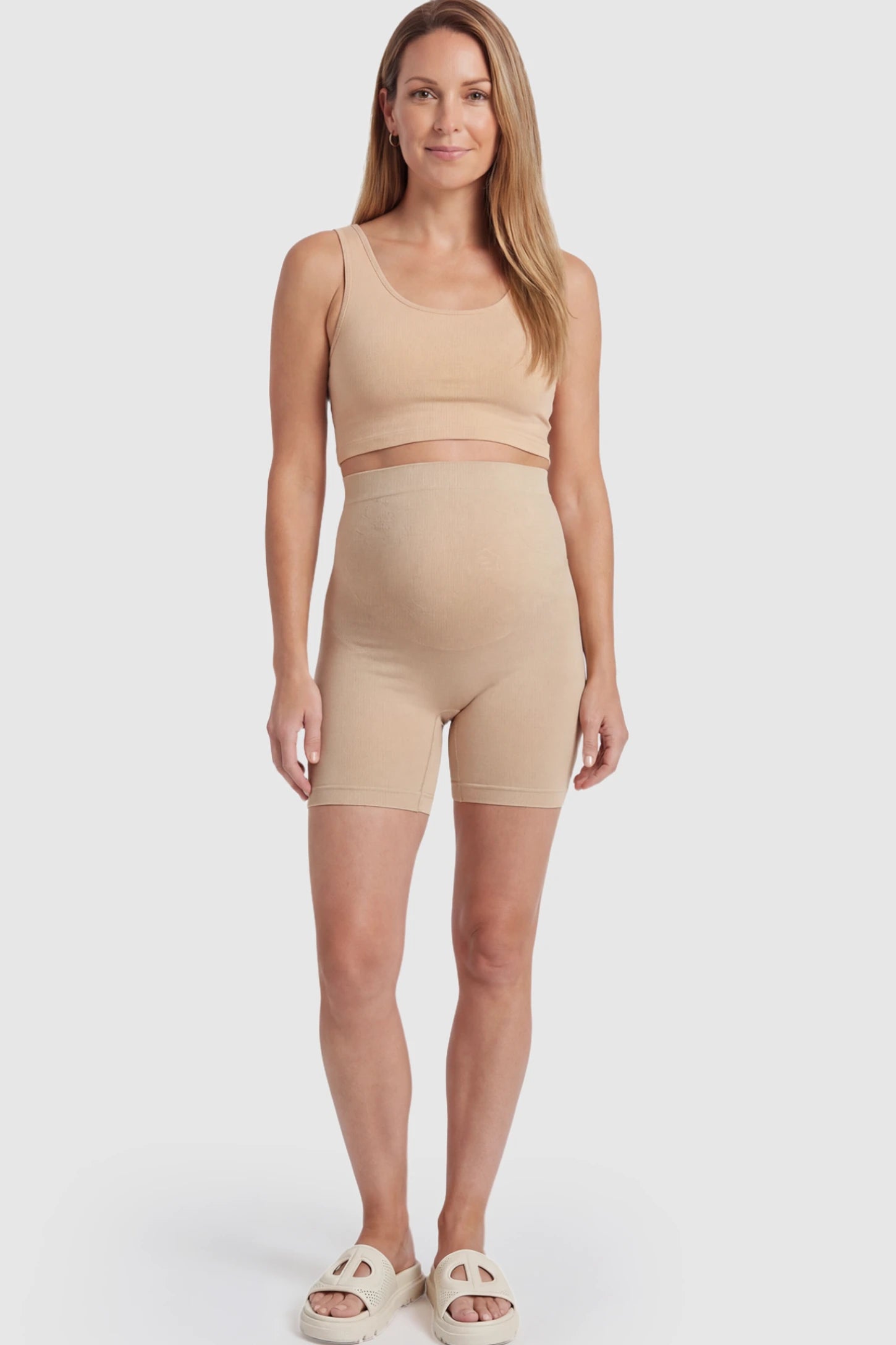 Seamless High Waisted Maternity Shapewear Shorts Seamless High-Waisted Mid Thigh Maternity Shapewear Shorts in Nude featuring a smooth belly support panel on a postpartum model.