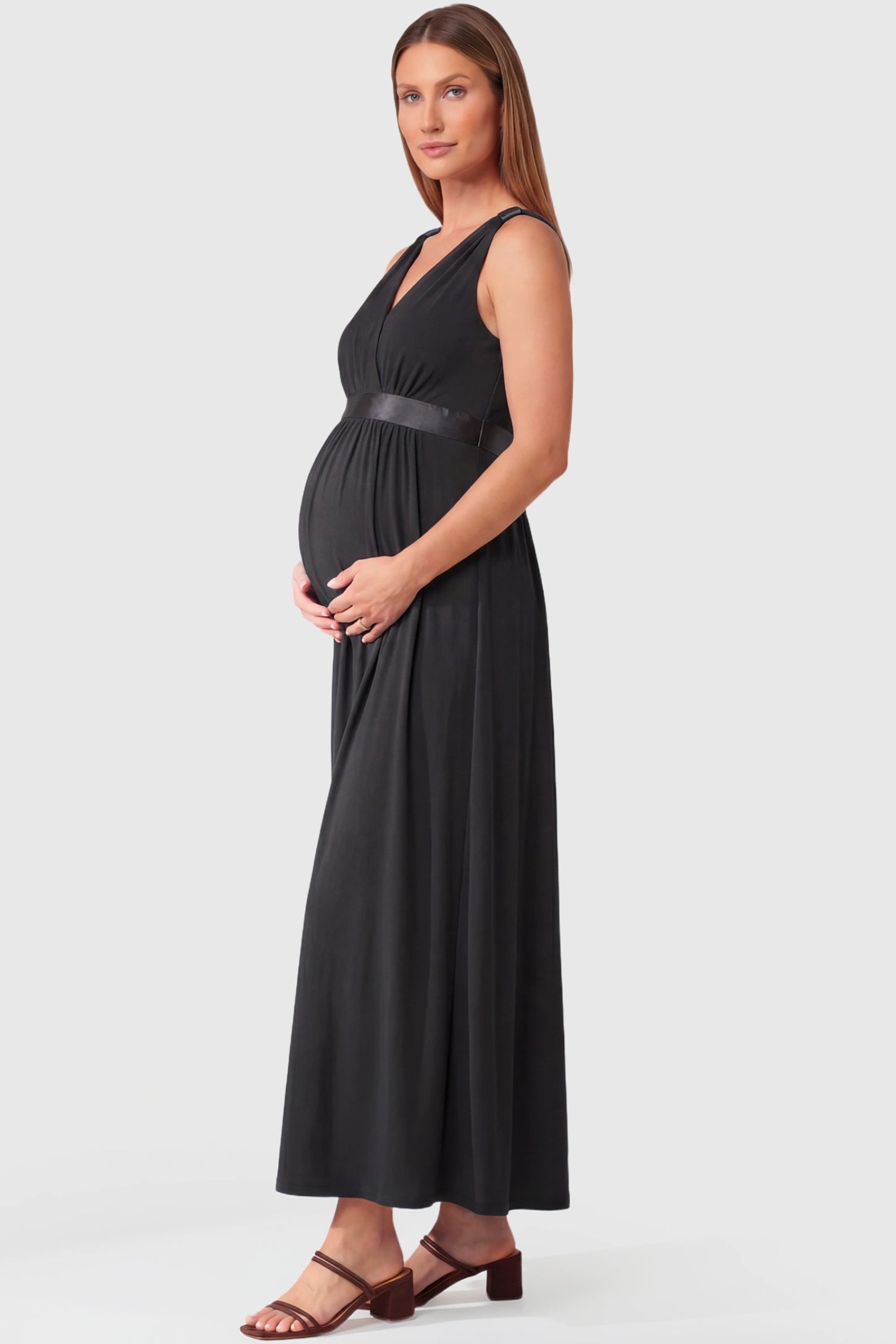 Sleeveless Faux Wrap Maternity & Nursing Maxi Dress Sleeveless Faux Wrap Maternity & Nursing Maxi Dress in black featuring V-neckline and empire waist on a pregnant model.