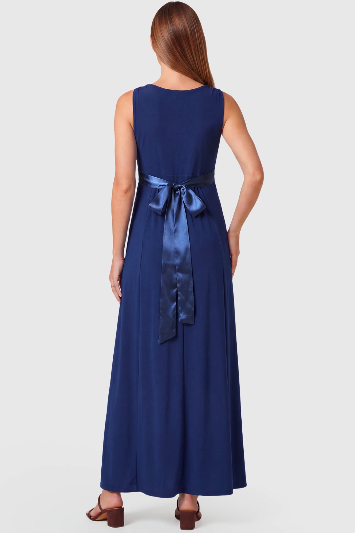Sleeveless Faux Wrap Maternity & Nursing Maxi Dress Sleeveless Faux Wrap Maternity & Nursing Maxi Dress in dark blue featuring bow tie and empire waist on a pregnant model.