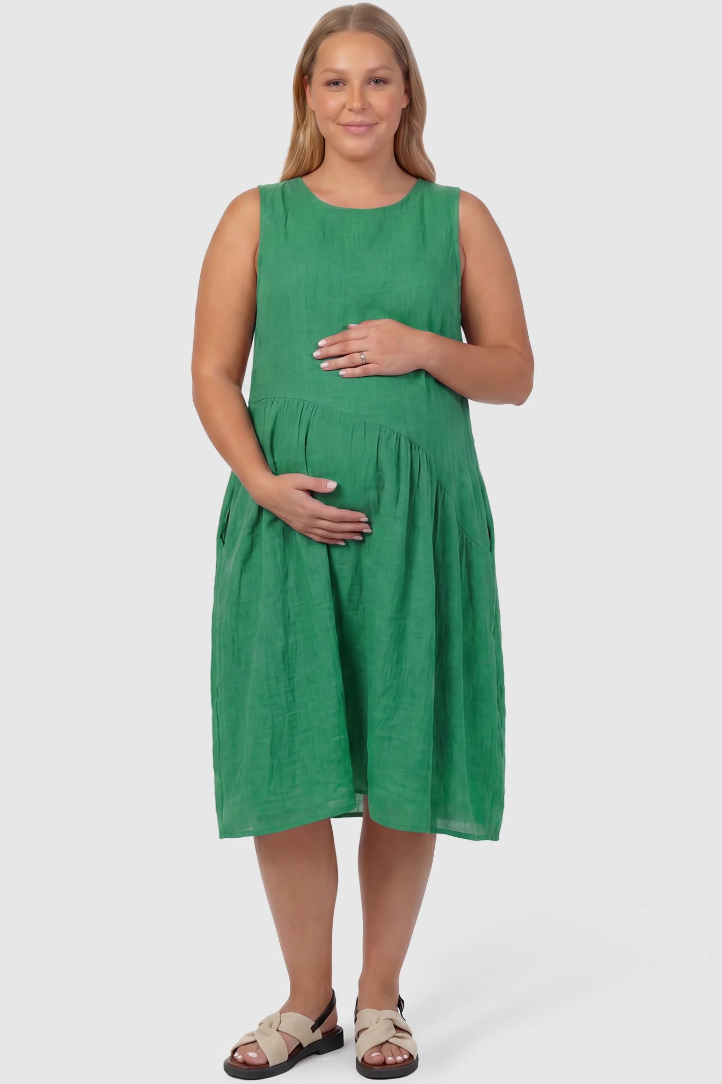 Sleeveless Pocketed A-Line Maternity Midi Dress Sleeveless pocketed A-line maternity midi dress in green with sleeveless cut, front view on plus-size model