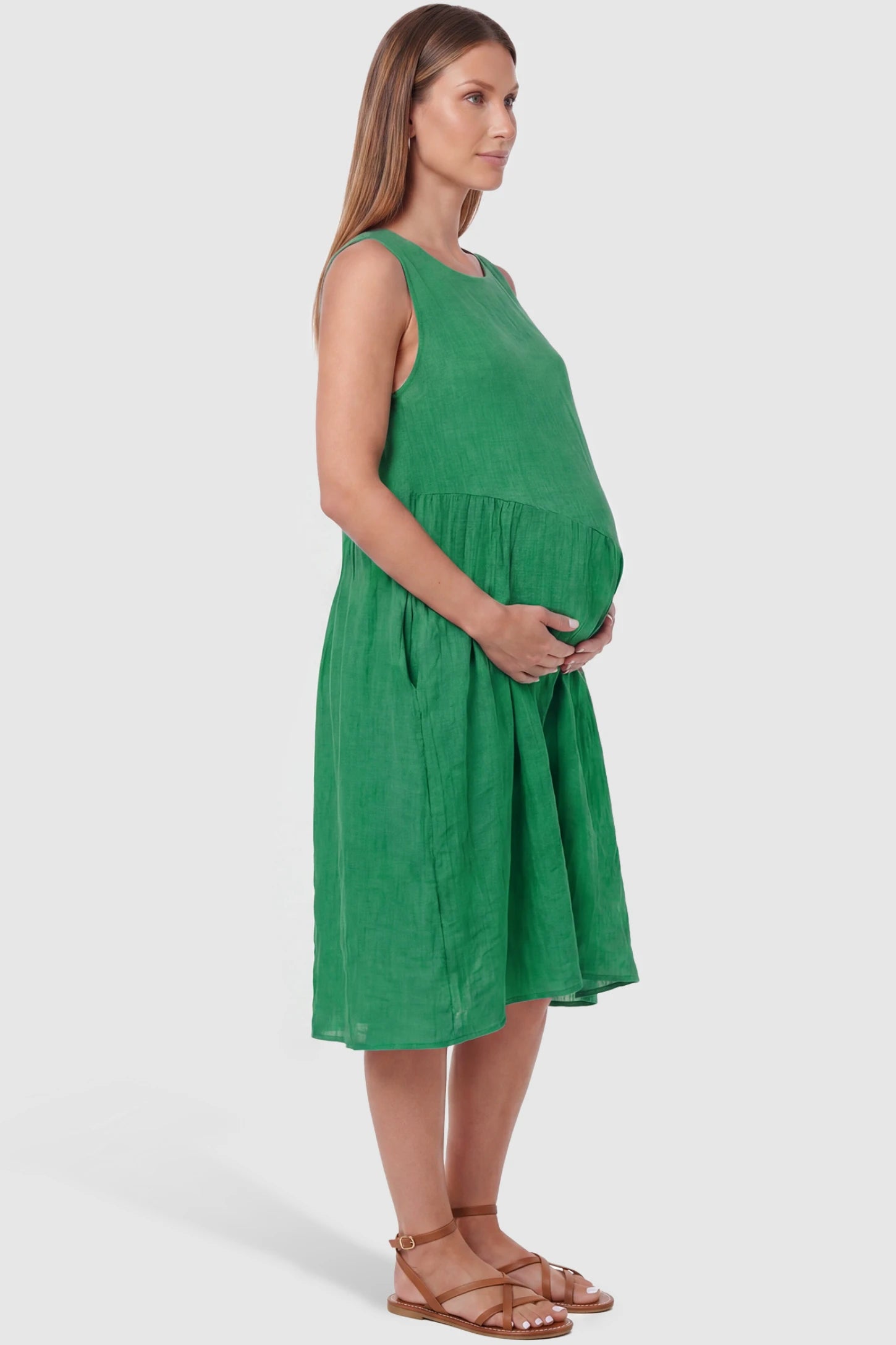 Sleeveless Pocketed A-Line Maternity Midi Dress Sleeveless pocketed A-line maternity midi dress in green with sleeveless cut, side view on pregnant model
