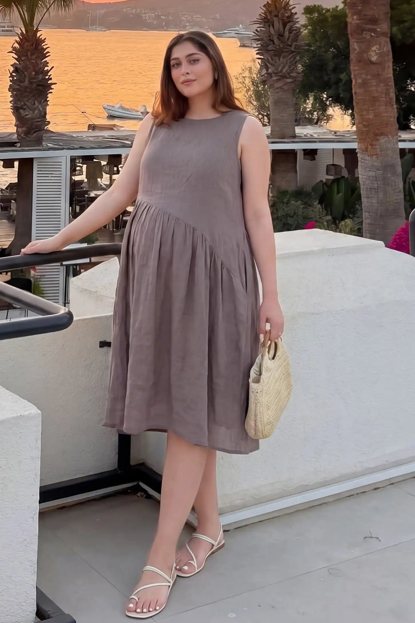 Sleeveless Pocketed A-Line Maternity Midi Dress Sleeveless pocketed A-line maternity midi dress in light taupe with sleeveless cut, front view on pregnant model