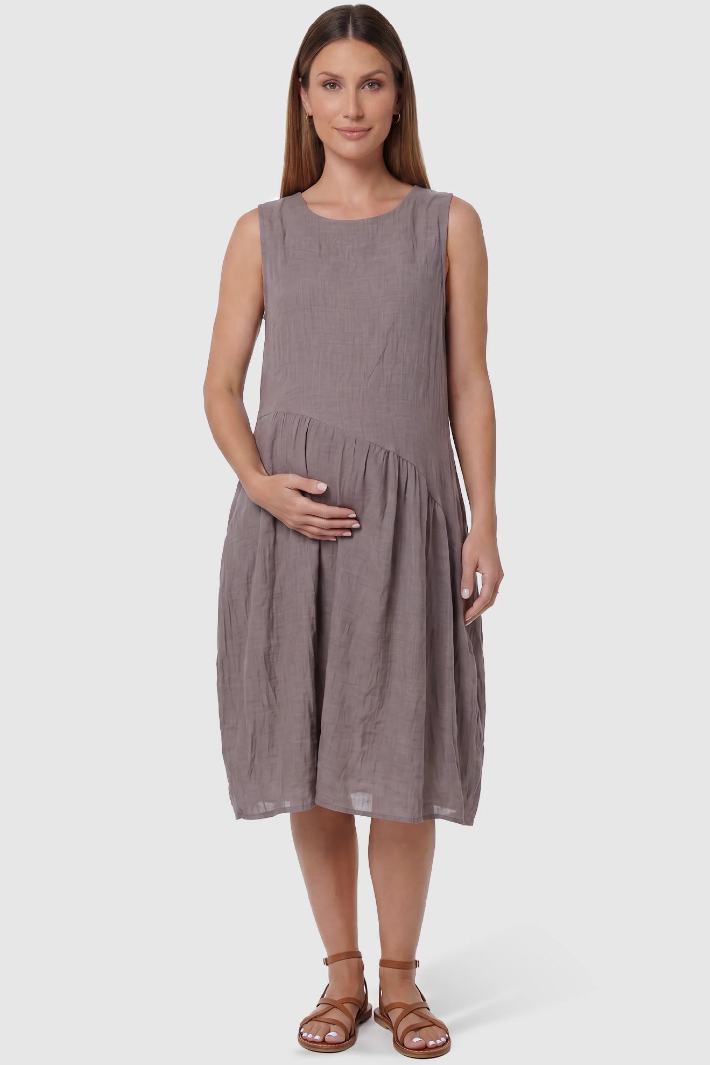 Sleeveless Pocketed A-Line Maternity Midi Dress Sleeveless pocketed A-line maternity midi dress in light taupe with sleeveless cut, front view on pregnant model