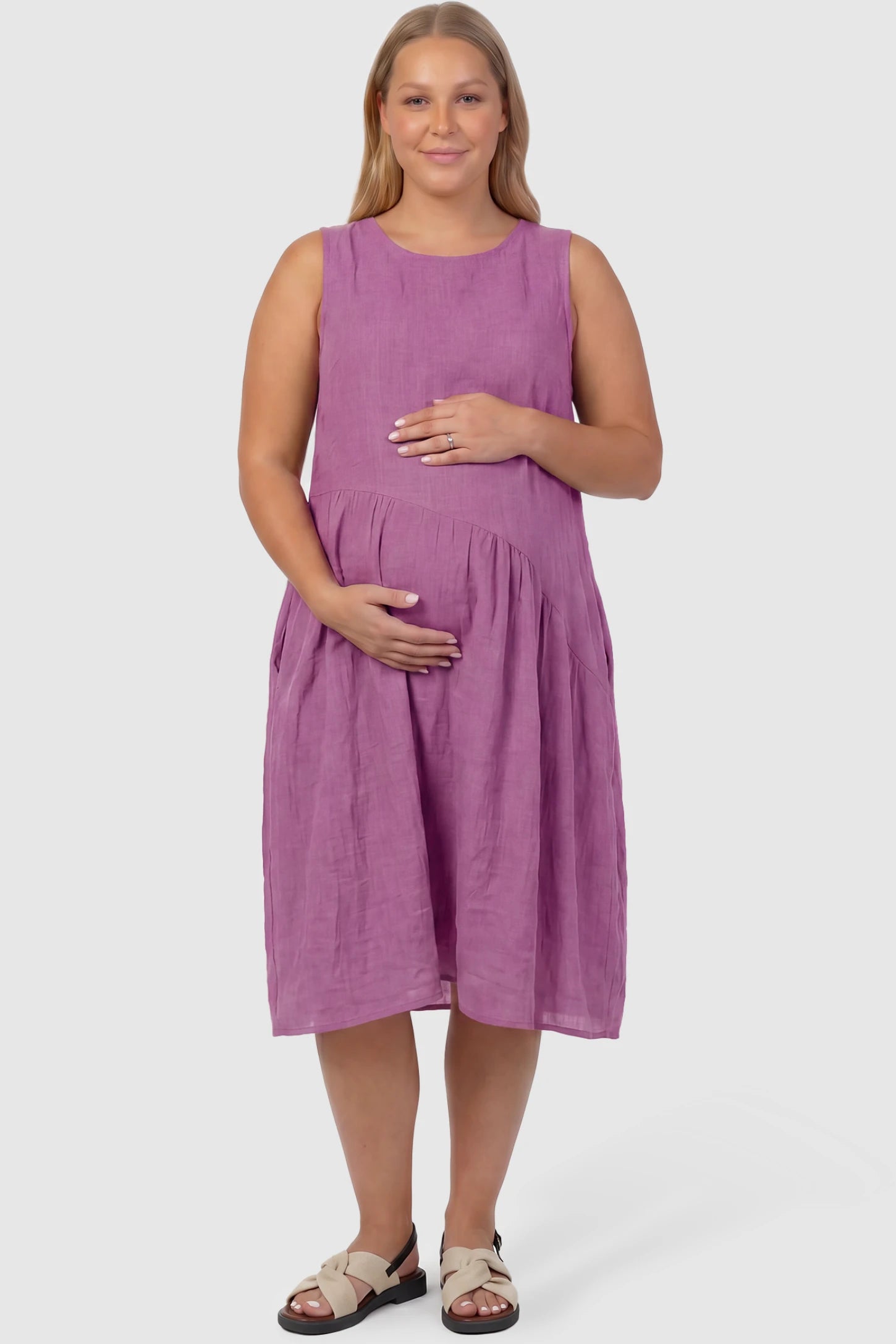 Sleeveless Pocketed A-Line Maternity Midi Dress Sleeveless pocketed A-line maternity midi dress in pink with sleeveless cut, front view on plus-size model