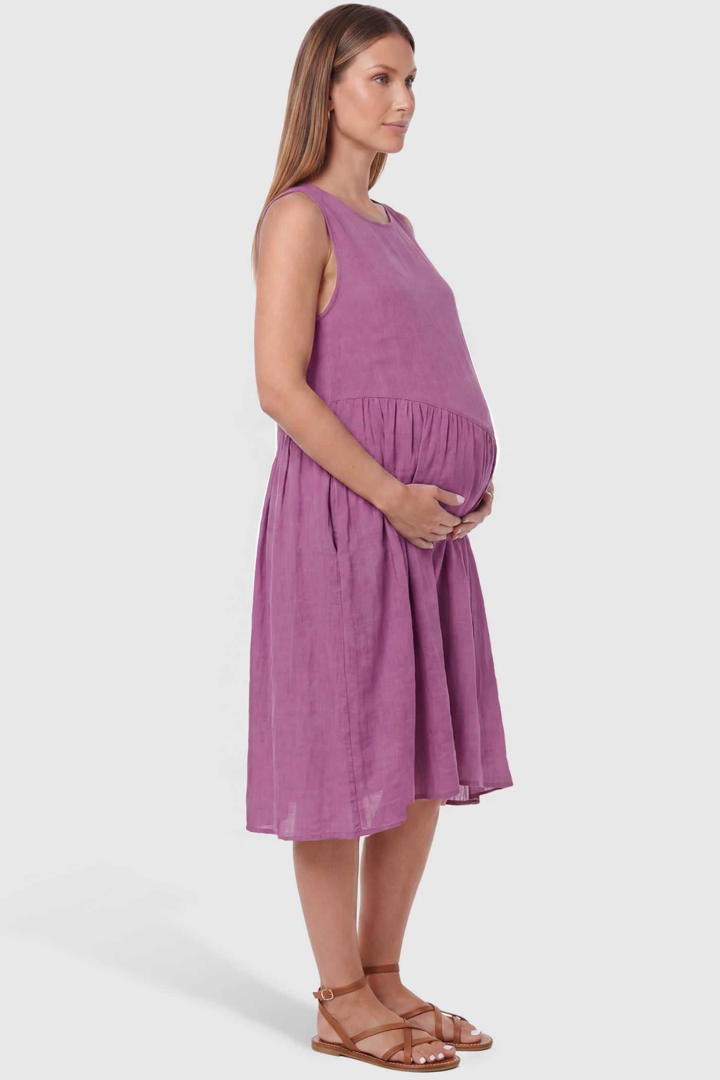 Sleeveless Pocketed A-Line Maternity Midi Dress Sleeveless pocketed A-line maternity midi dress in pink with sleeveless cut, side view on pregnant model