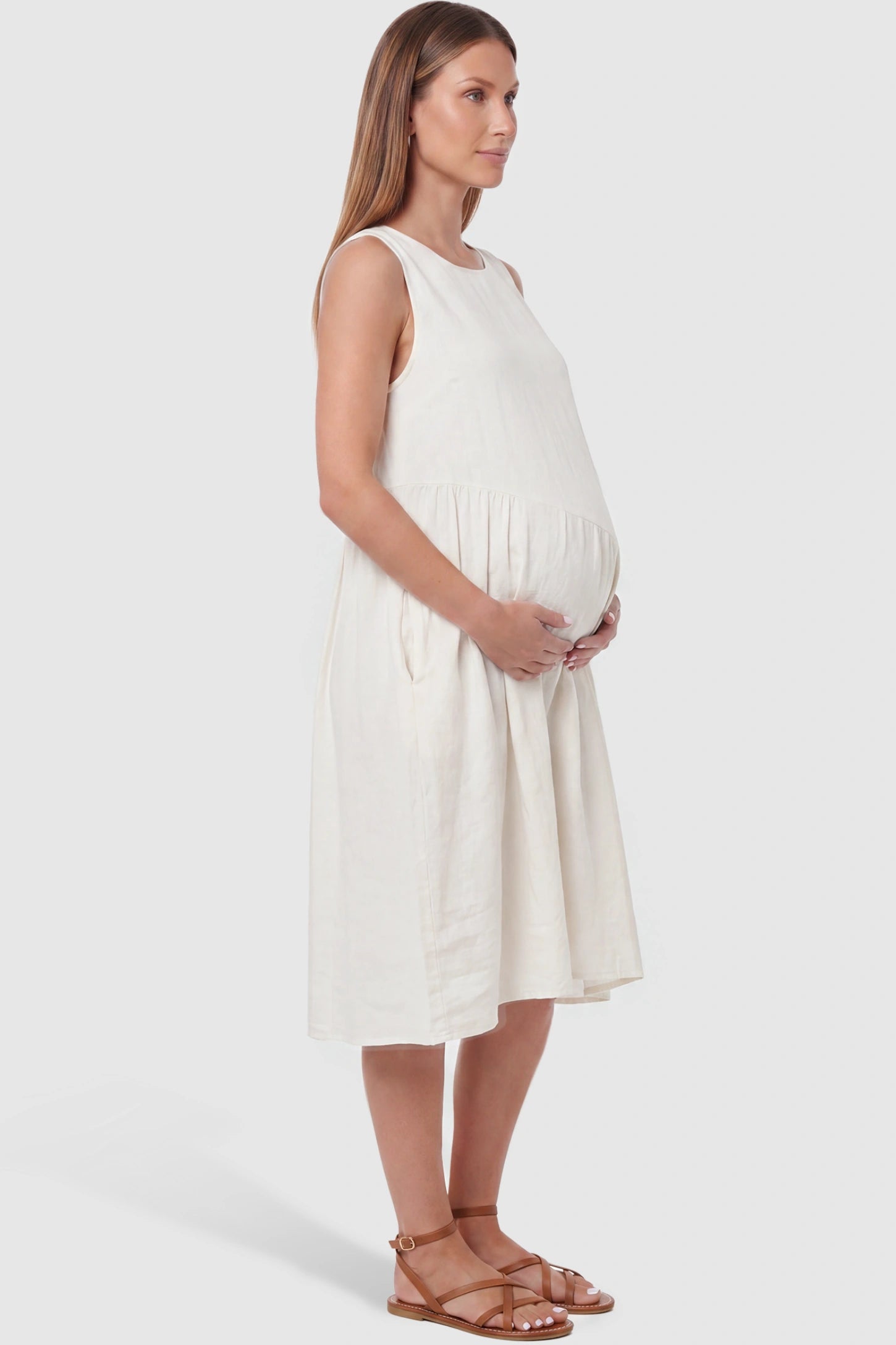 Sleeveless Pocketed A-Line Maternity Midi Dress Sleeveless pocketed A-line maternity midi dress in white with sleeveless cut, side view on pregnant model