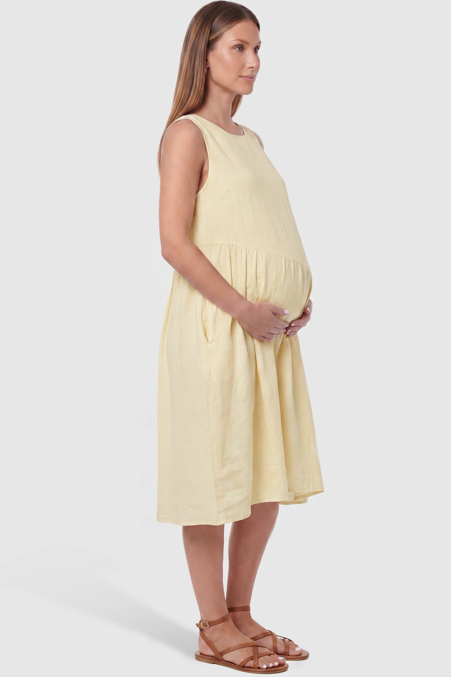 Sleeveless Pocketed A-Line Maternity Midi Dress Sleeveless pocketed A-line maternity midi dress in yellow with sleeveless cut, side view on pregnant model