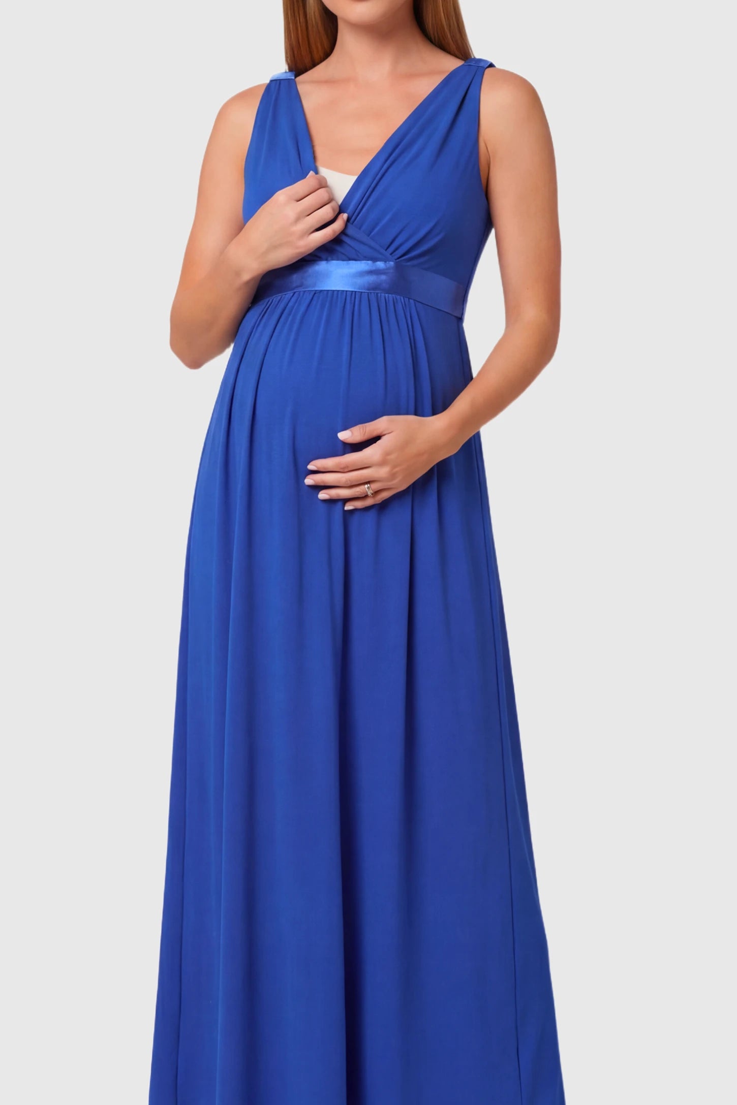 Sleeveless Faux Wrap Maternity & Nursing Maxi Dress Sleeveless Faux Wrap Maternity & Nursing Maxi Dress in royal blue featuring V-neckline and empire waist on a pregnant model.