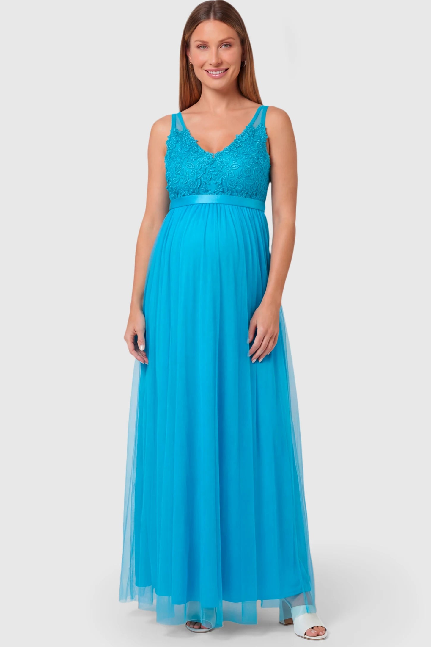Sleeveless A-line Maternity Gown Sleeveless A-line Maternity Gown in peacock blue featuring lace-trimmed V-neck and empire waist on pregnant model.