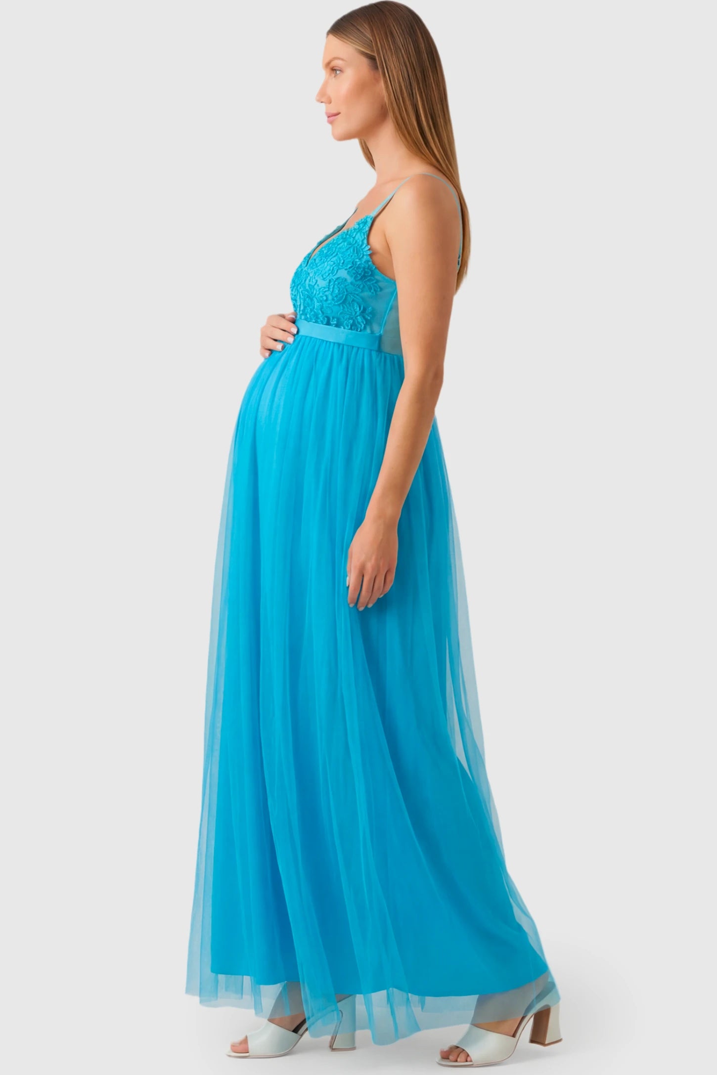 Sleeveless A-line Maternity Gown Sleeveless A-line Maternity Gown in peacock blue featuring lace-trimmed V-neck and empire waist on pregnant model.