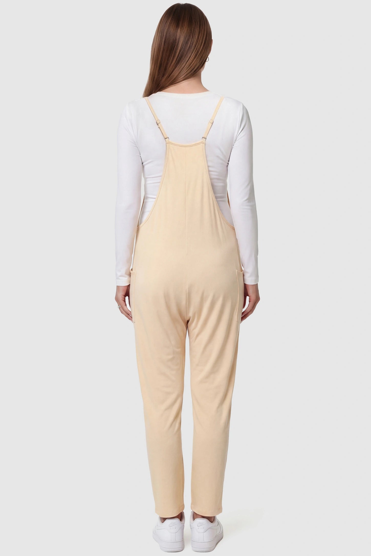 Adjustable Strap Pocketed Relaxed Maternity Jumpsuit Adjustable Strap Relaxed Maternity Jumpsuit in Beige featuring a loose fit on a pregnant model.