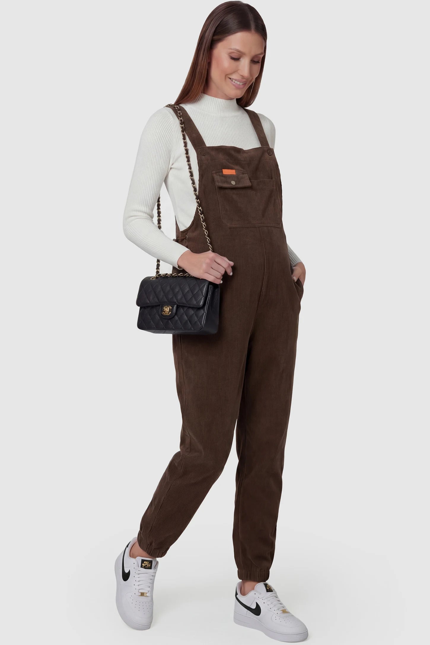 Adjustable strap loose fit maternity overalls in brown featuring wide leg design on a pregnant model