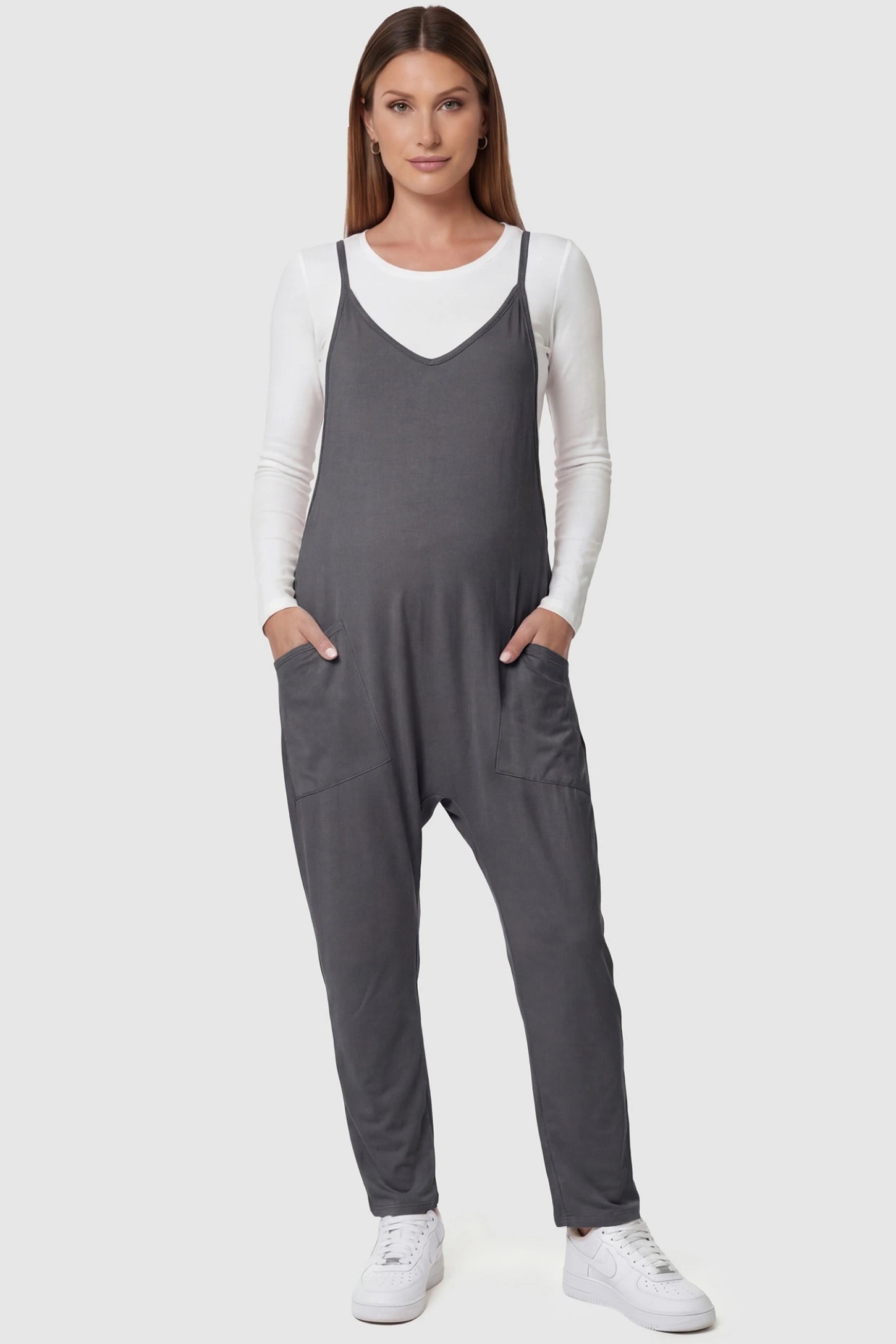 Adjustable Strap Pocketed Relaxed Maternity Jumpsuit Adjustable Strap Relaxed Maternity Jumpsuit in Dark Gray featuring a loose fit and functional pockets on a pregnant model.