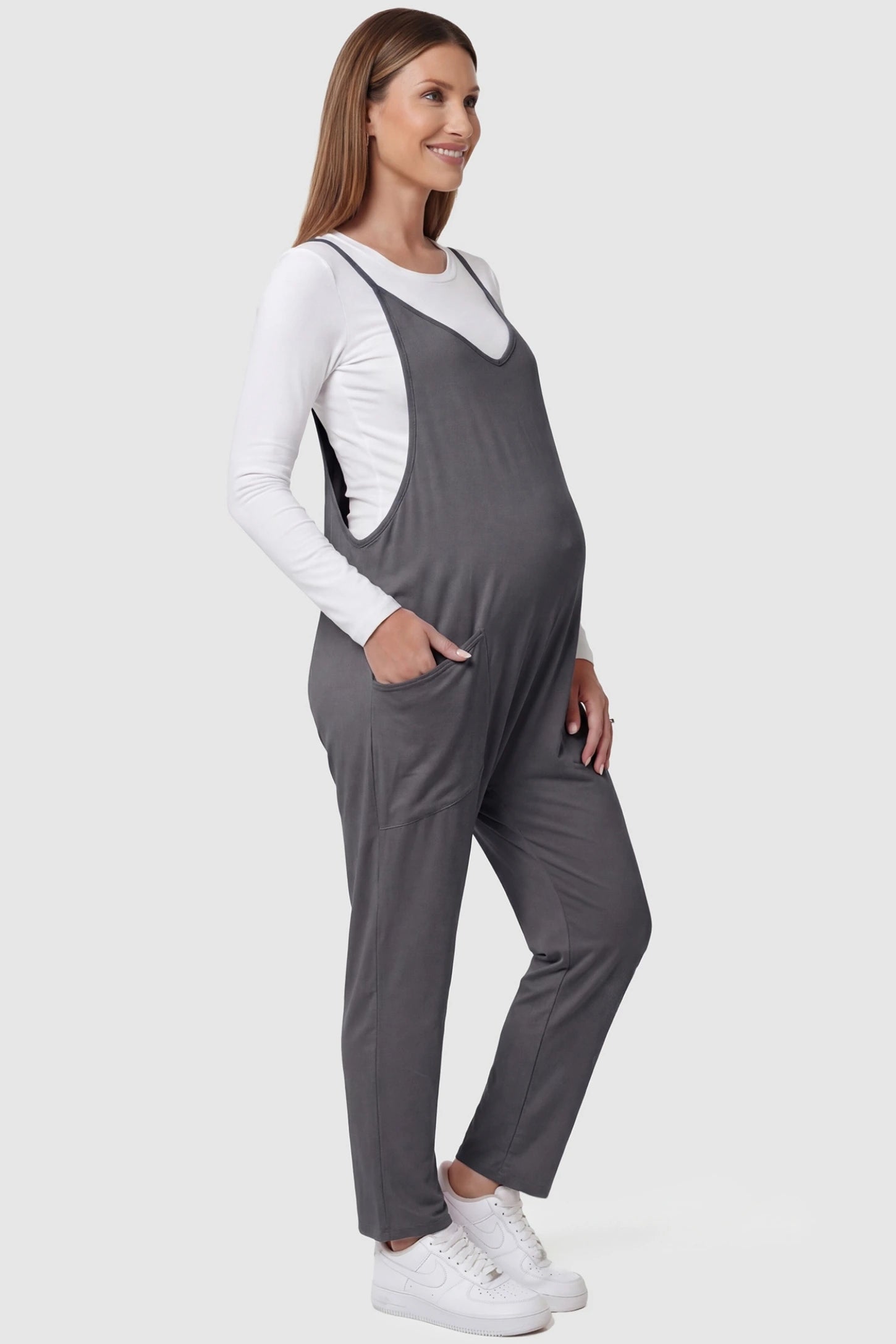 Adjustable Strap Pocketed Relaxed Maternity Jumpsuit Adjustable Strap Relaxed Maternity Jumpsuit in Dark Gray featuring a loose fit and functional pockets on a pregnant model.