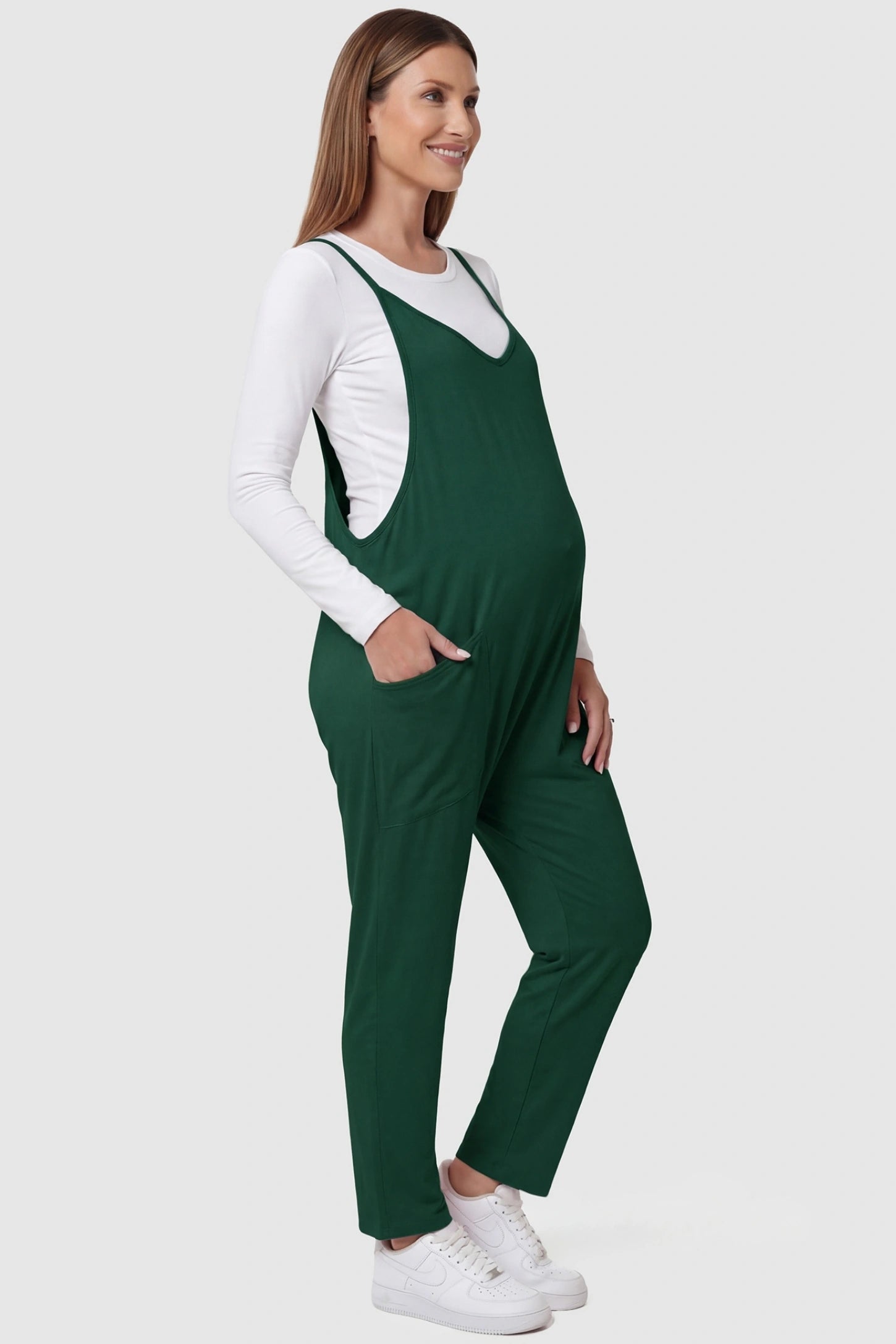 Adjustable Strap Pocketed Relaxed Maternity Jumpsuit Adjustable Strap Relaxed Maternity Jumpsuit in Dark Green featuring a loose fit and functional pockets on a pregnant model.