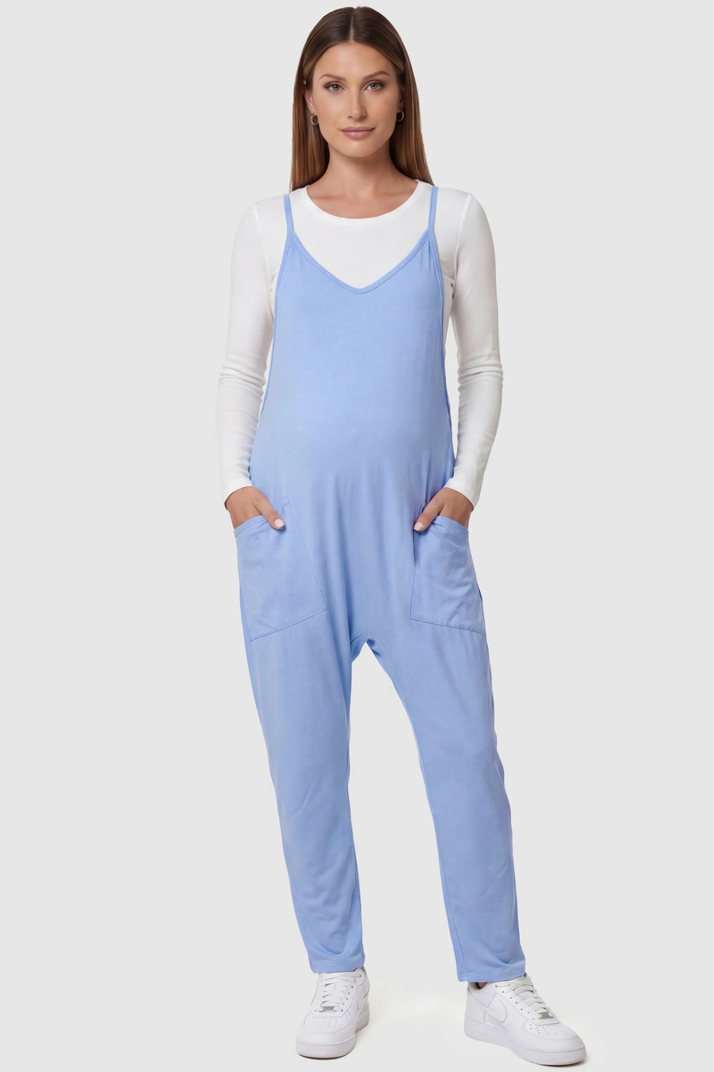 Adjustable Strap Pocketed Relaxed Maternity Jumpsuit Adjustable Strap Relaxed Maternity Jumpsuit in Light Blue featuring a loose fit and functional pockets on a pregnant model.