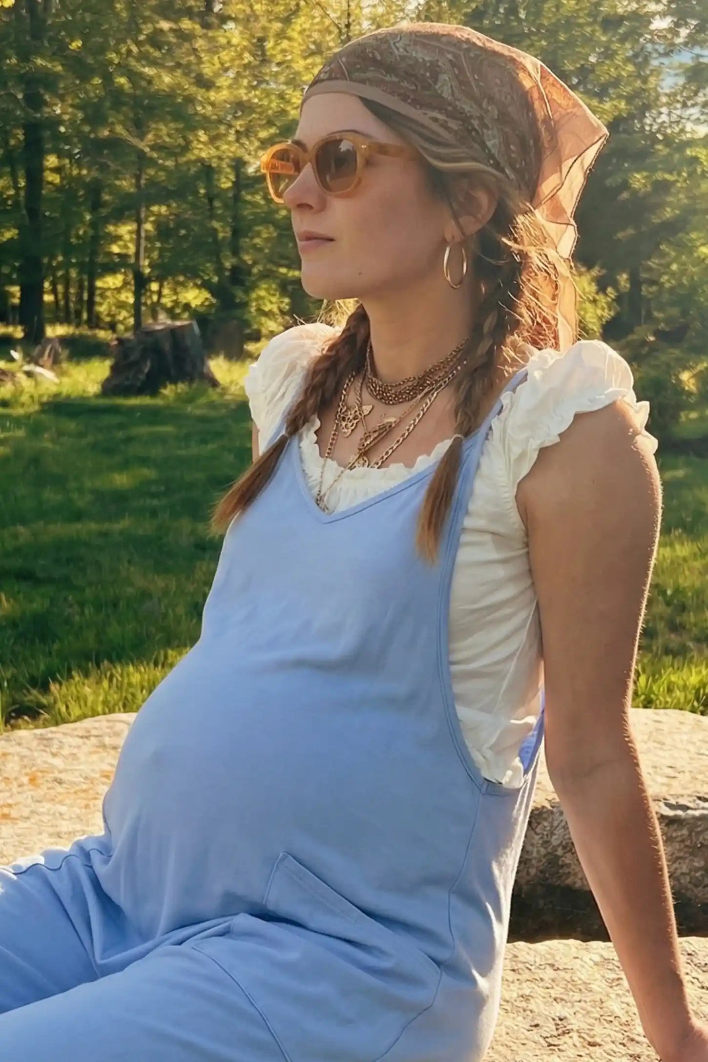 Adjustable Strap Pocketed Relaxed Maternity Jumpsuit Adjustable Strap Relaxed Maternity Jumpsuit in Light Blue featuring a loose fit and functional pockets on a pregnant model.