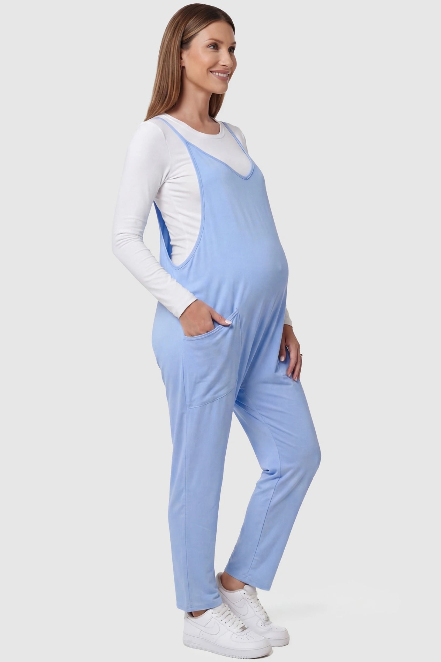 Adjustable Strap Pocketed Relaxed Maternity Jumpsuit Adjustable Strap Relaxed Maternity Jumpsuit in Light Blue featuring a loose fit and functional pockets on a pregnant model.