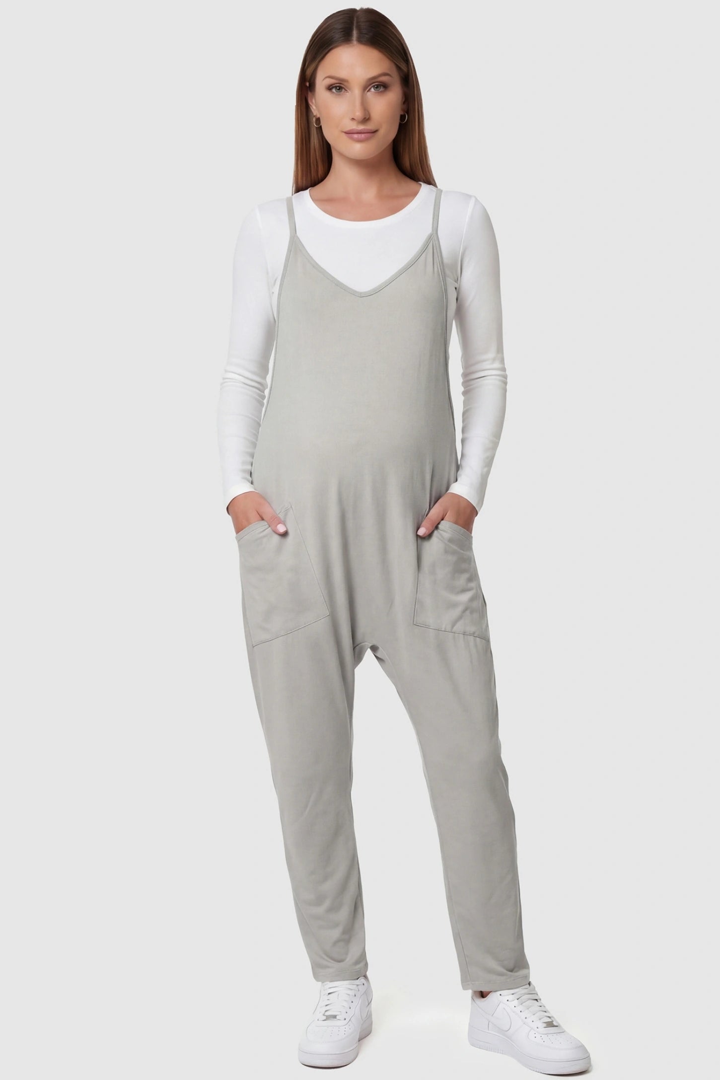 Adjustable Strap Pocketed Relaxed Maternity Jumpsuit Adjustable Strap Relaxed Maternity Jumpsuit in Light Gray featuring a loose fit and functional pockets on a pregnant model.