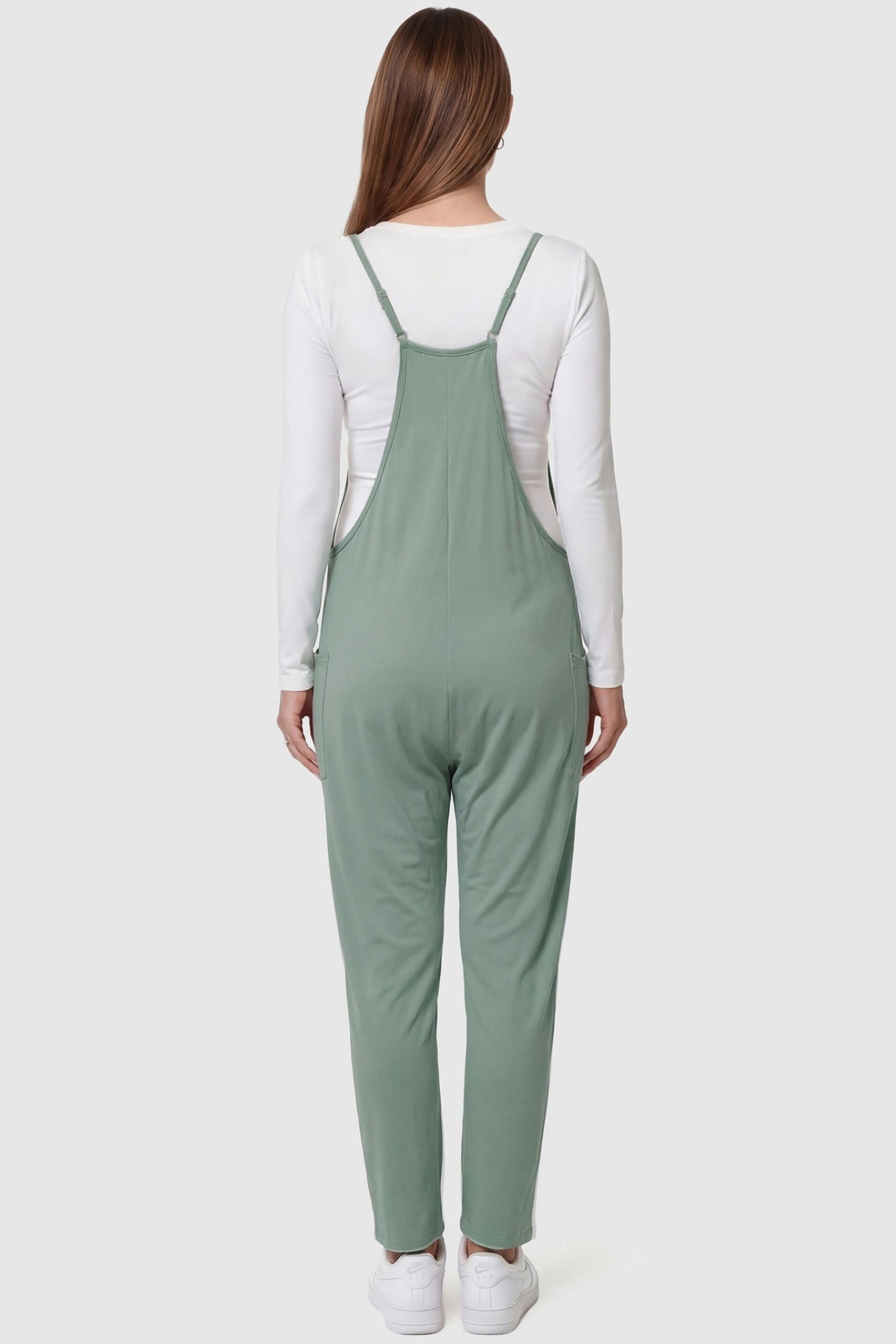 Adjustable Strap Pocketed Relaxed Maternity Jumpsuit Adjustable Strap Relaxed Maternity Jumpsuit in Light Green featuring a loose fit on a pregnant model.