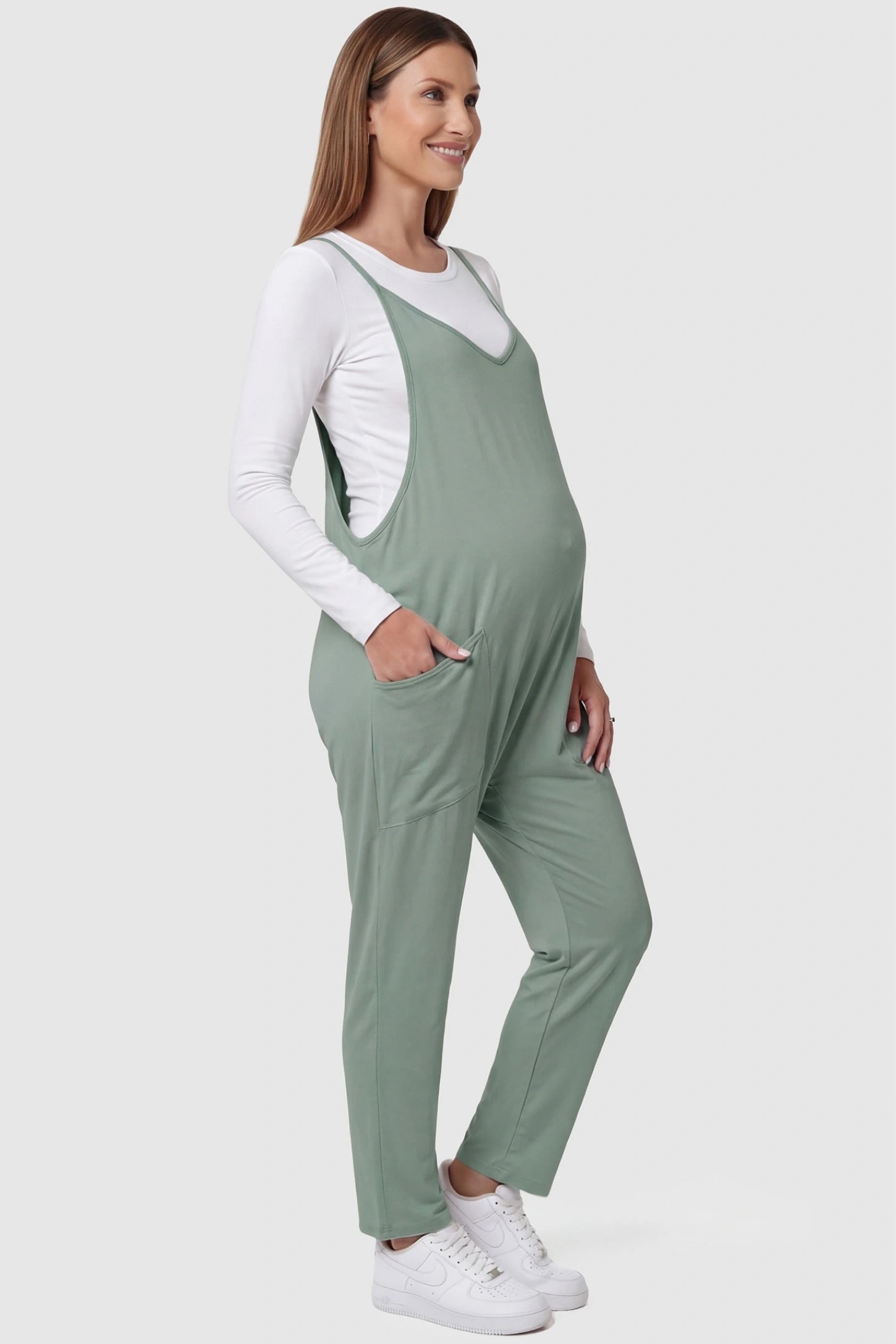 Adjustable Strap Pocketed Relaxed Maternity Jumpsuit Adjustable Strap Relaxed Maternity Jumpsuit in Light Green featuring a loose fit and functional pockets on a pregnant model.