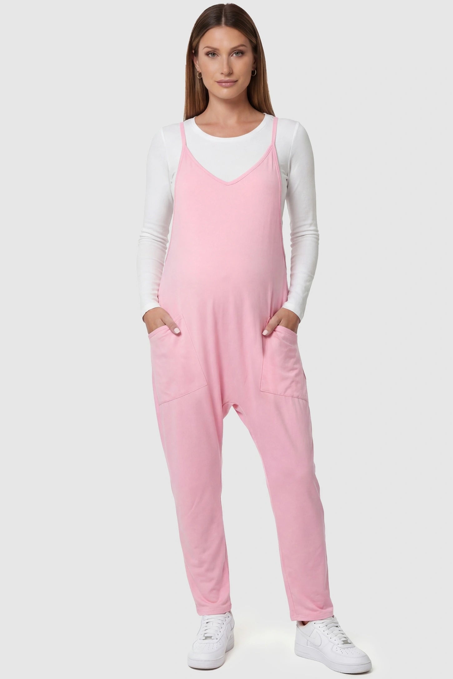 Adjustable Strap Pocketed Relaxed Maternity Jumpsuit Adjustable Strap Relaxed Maternity Jumpsuit in Pink featuring a loose fit and functional pockets on a pregnant model.