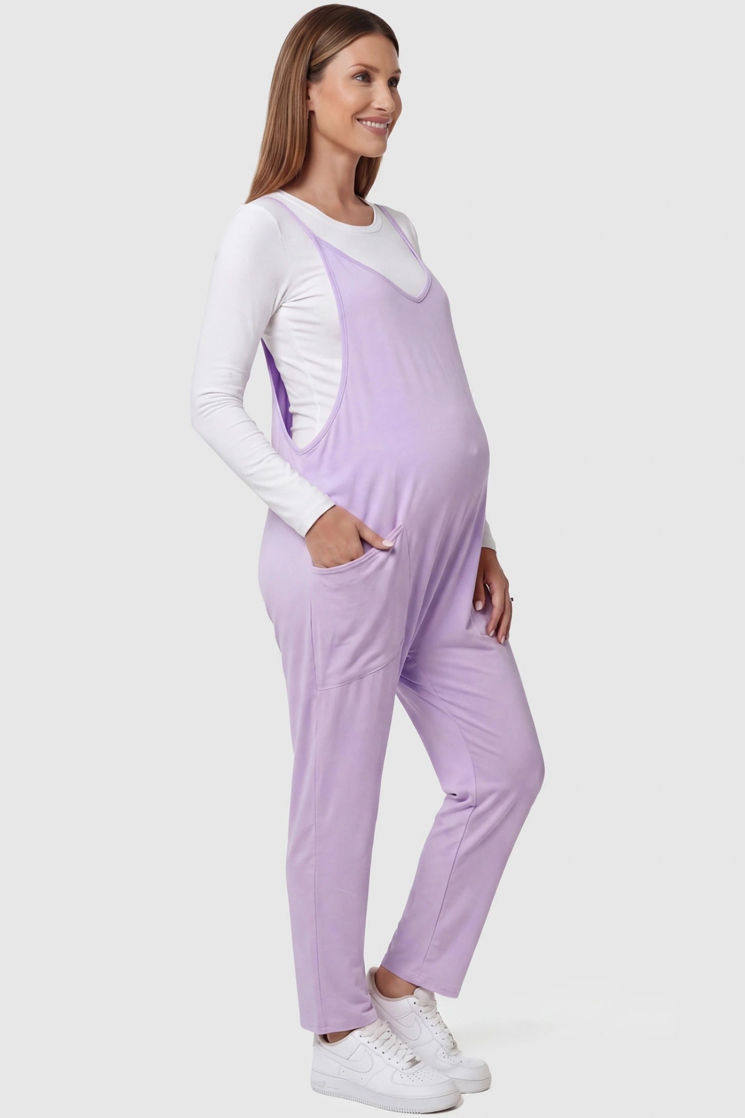 Adjustable Strap Pocketed Relaxed Maternity Jumpsuit Adjustable Strap Relaxed Maternity Jumpsuit in Purple featuring a loose fit and functional pockets on a pregnant model.