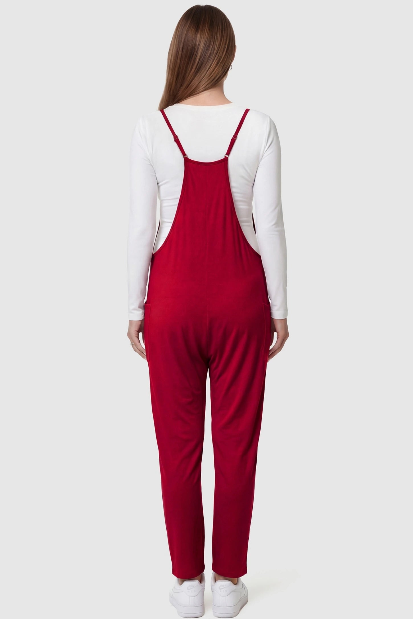 Adjustable Strap Pocketed Relaxed Maternity Jumpsuit Adjustable Strap Relaxed Maternity Jumpsuit in Wine Red featuring a loose fit on a pregnant model.