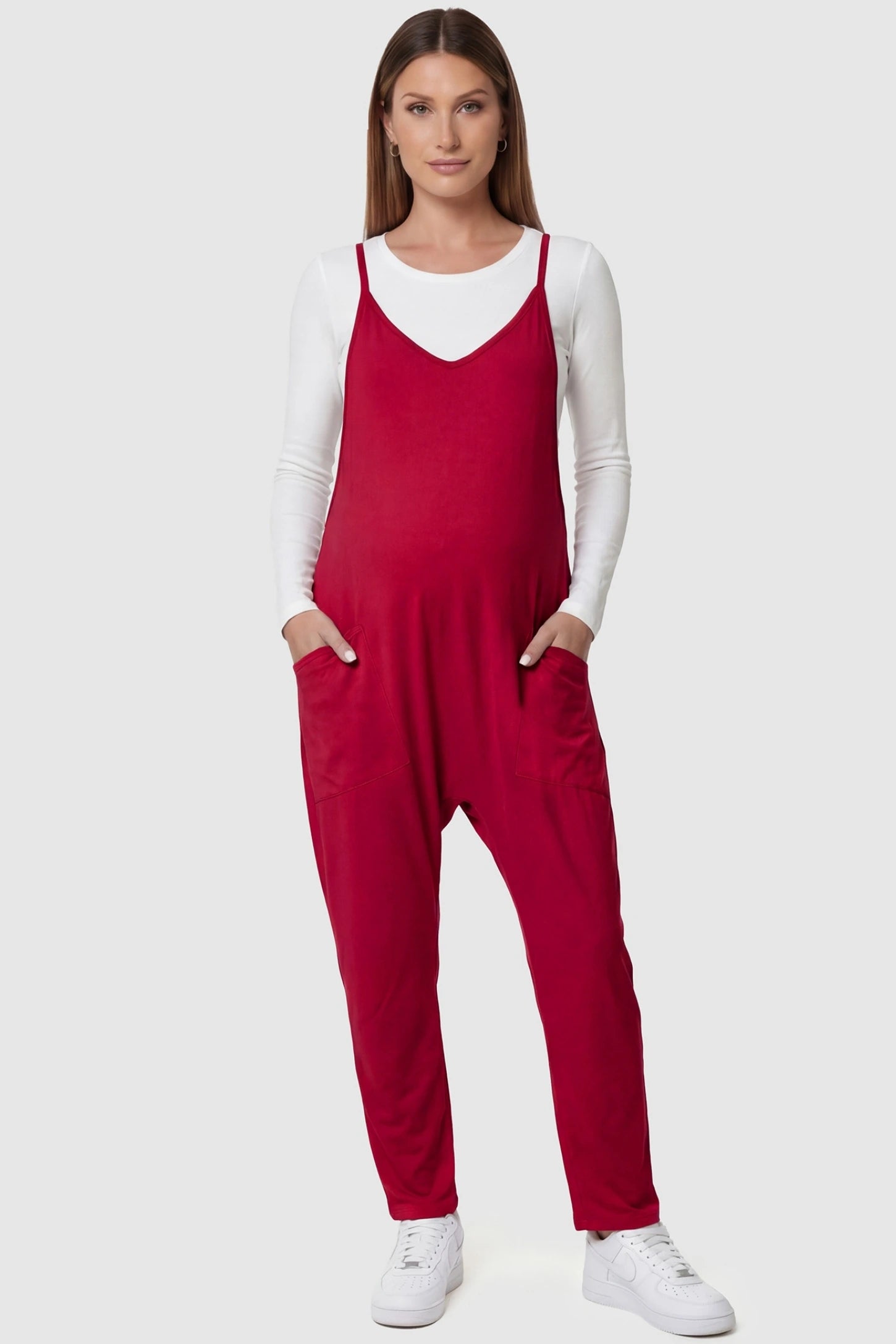 Adjustable Strap Pocketed Relaxed Maternity Jumpsuit Adjustable Strap Relaxed Maternity Jumpsuit in Wine Red featuring a loose fit and functional pockets on a pregnant model.