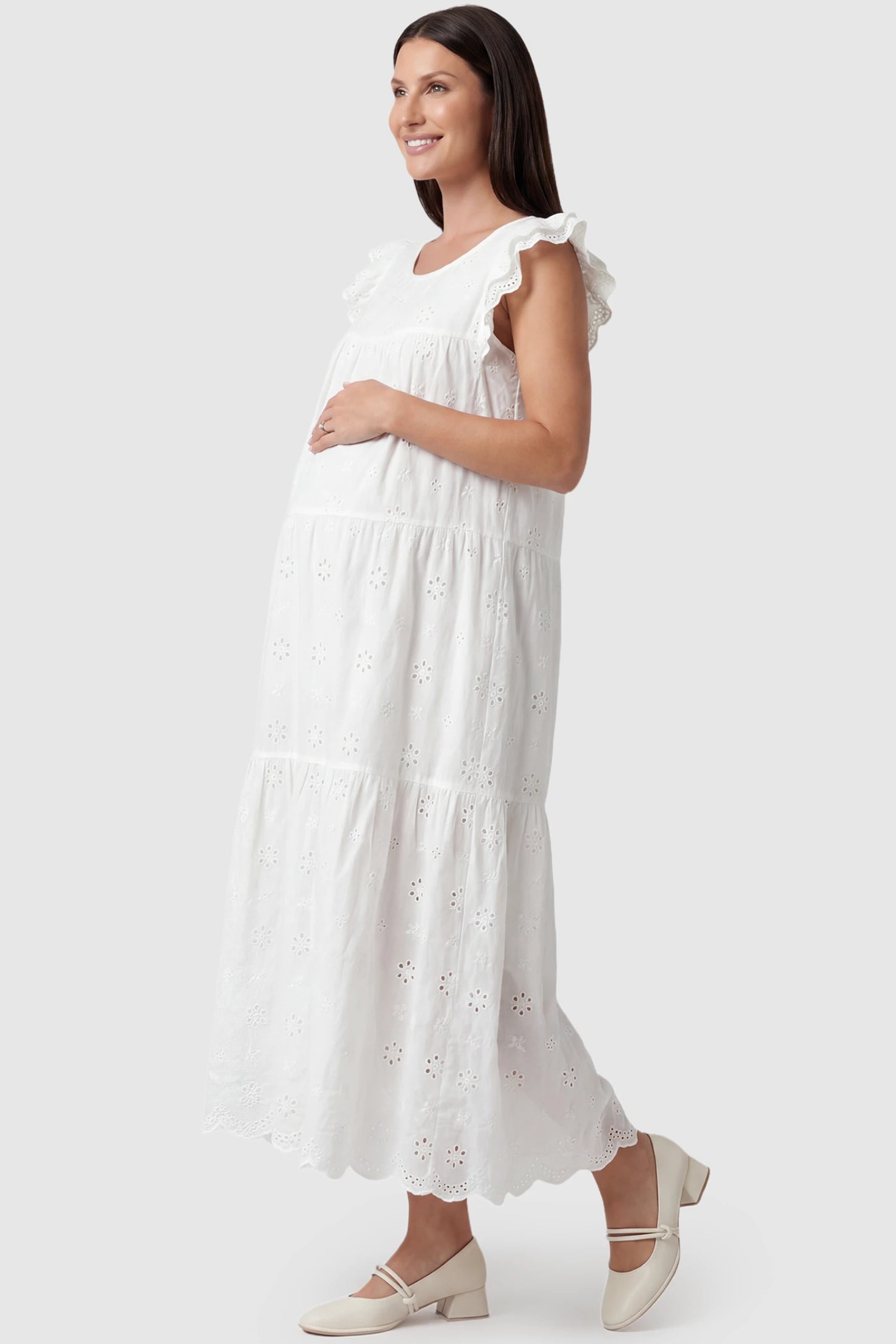 Anglaise Lace Ruffled Sleeve Tiered Maternity Maxi Dress Anglaise lace ruffled sleeve tiered maternity maxi dress in white with delicate lace detail, side view on pregnant model