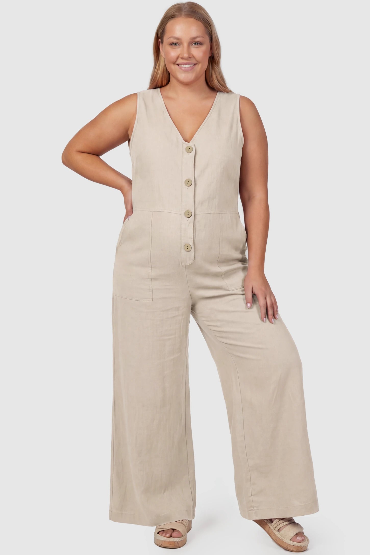 Wide-Leg V-Neck Button-Front Maternity Jumpsuit Wide-leg V-neck button-front maternity jumpsuit in beige with sleeveless V-neckline and button-front detail, front view on plus-size model