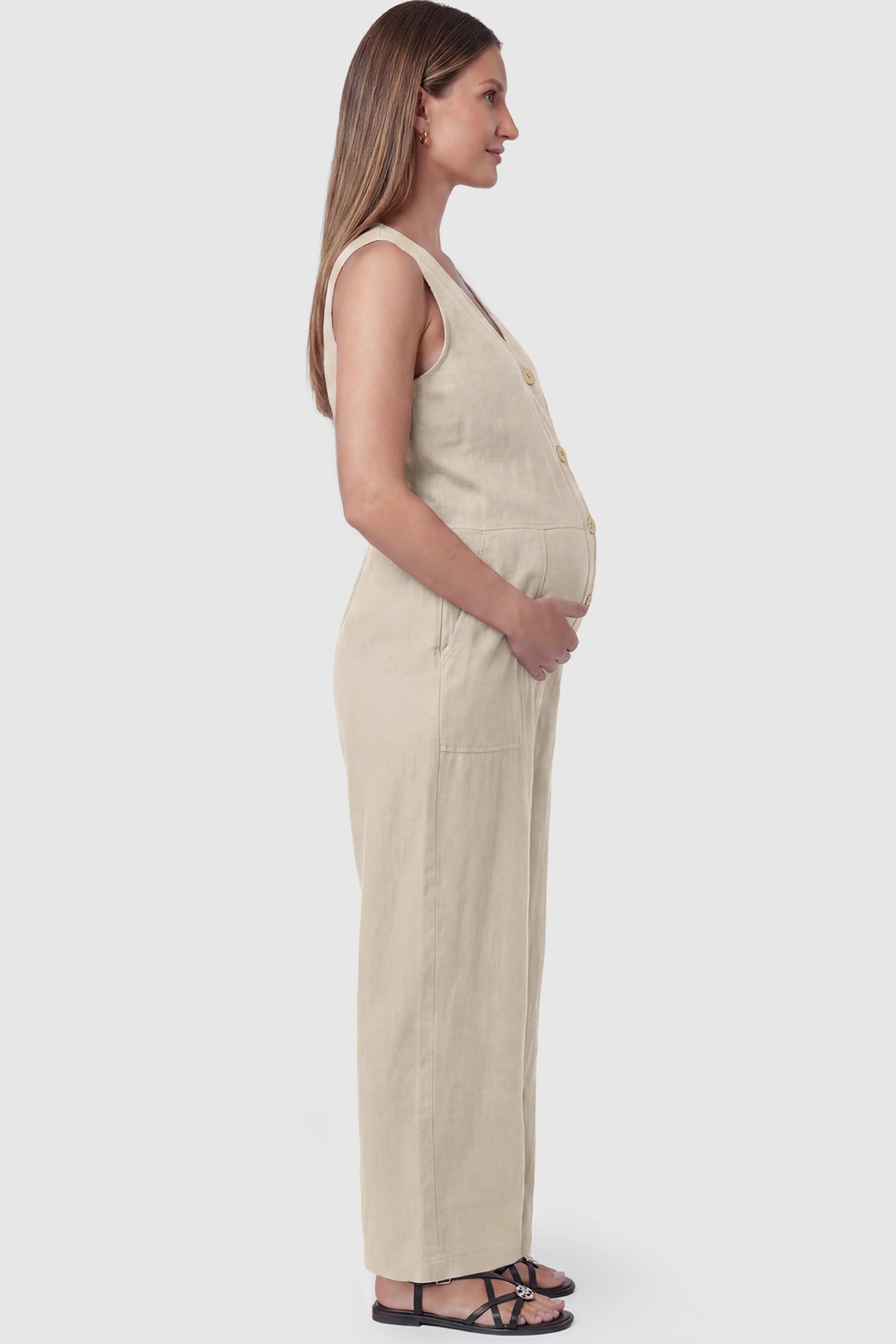 Wide-Leg V-Neck Button-Front Maternity Jumpsuit Wide-leg V-neck button-front maternity jumpsuit in beige with sleeveless cut, side view on pregnant model