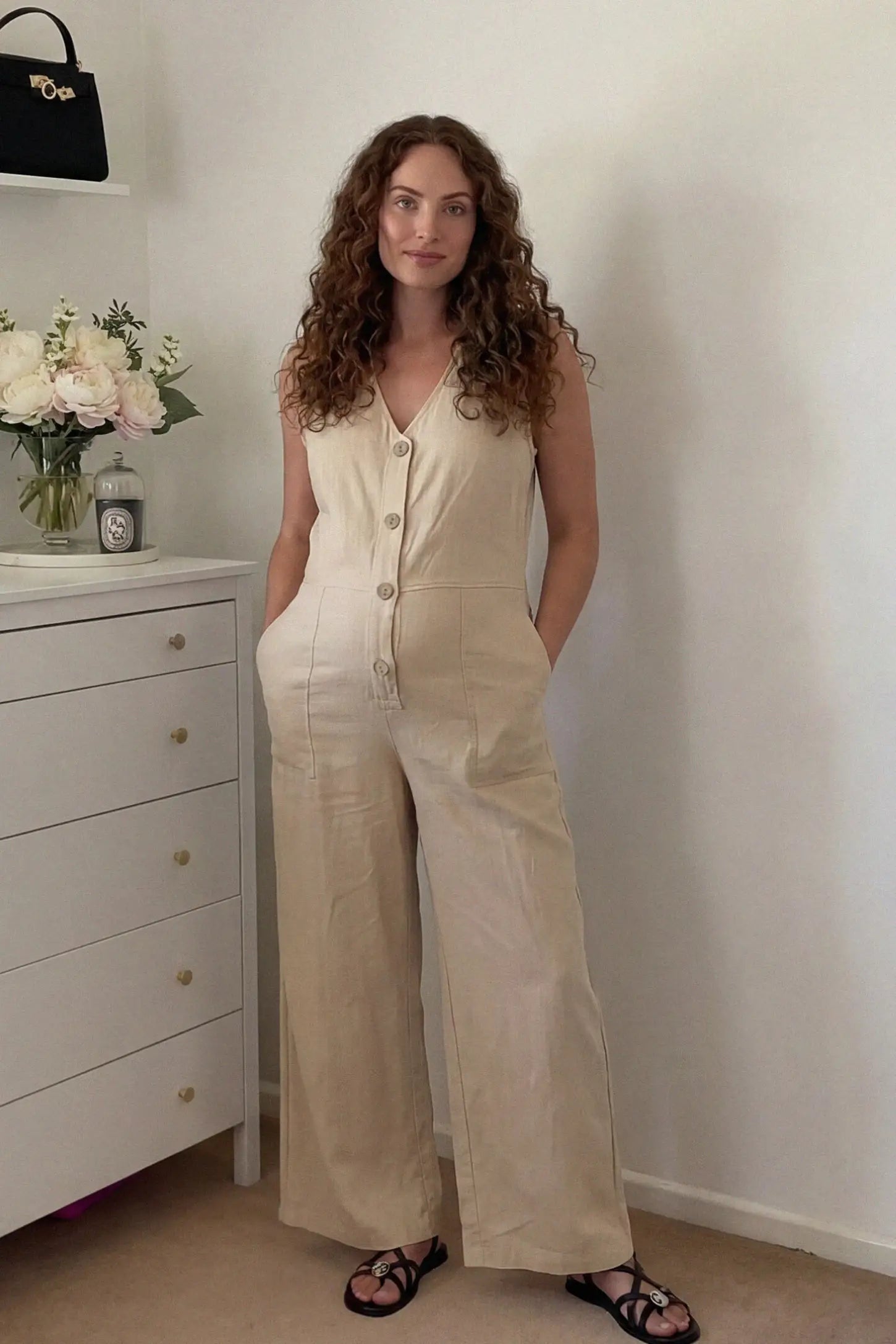 Wide-Leg V-Neck Button-Front Maternity Jumpsuit Wide-leg V-neck button-front maternity jumpsuit in beige with sleeveless V-neckline and button-front detail, front view on pregnant model