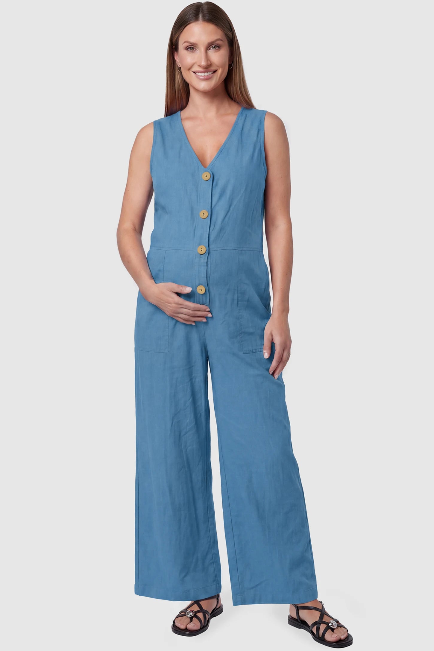 Wide-Leg V-Neck Button-Front Maternity Jumpsuit Wide-leg V-neck button-front maternity jumpsuit in blue with sleeveless V-neckline and button-front detail, front view on pregnant model