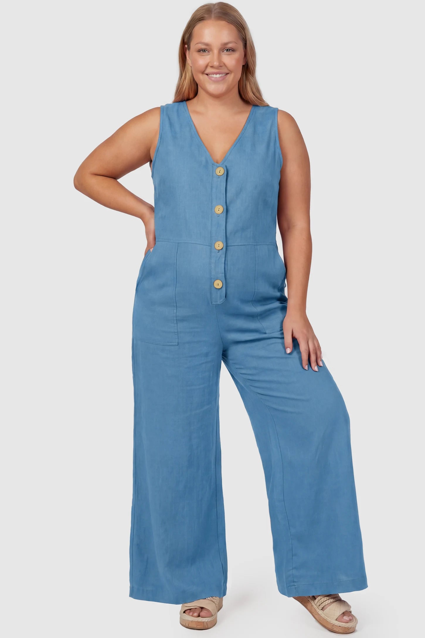 Wide-Leg V-Neck Button-Front Maternity Jumpsuit Wide-leg V-neck button-front maternity jumpsuit in blue with sleeveless V-neckline and button-front detail, front view on plus-size model