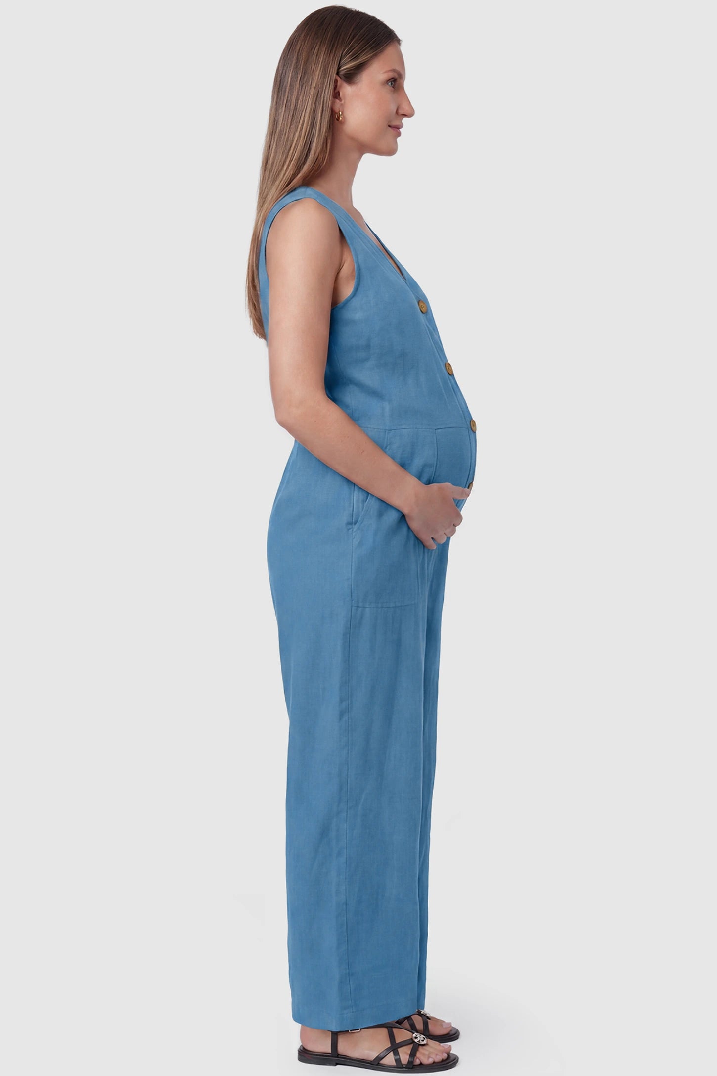 Wide-Leg V-Neck Button-Front Maternity Jumpsuit Wide-leg V-neck button-front maternity jumpsuit in blue with sleeveless cut, side view on pregnant model