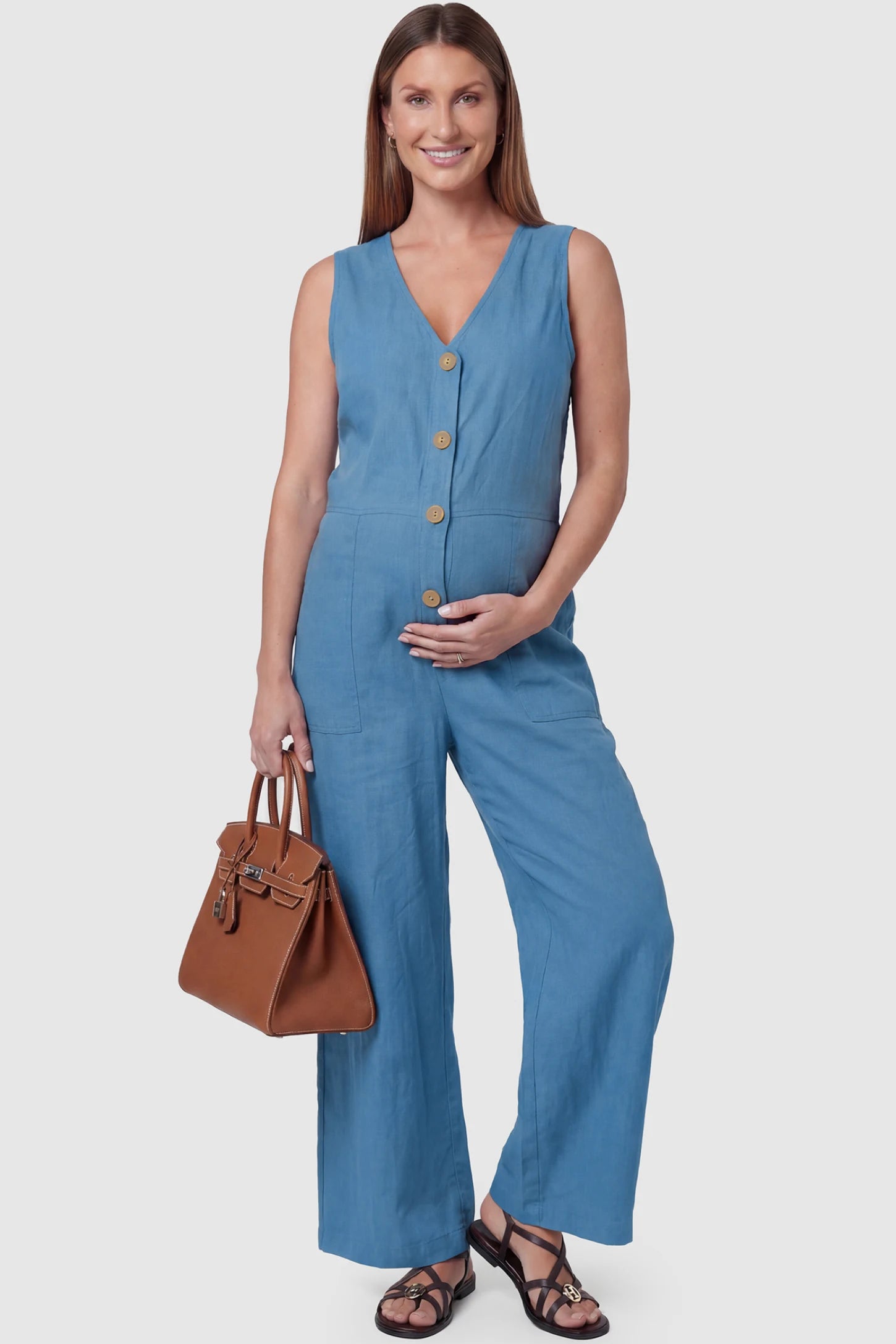 Wide-Leg V-Neck Button-Front Maternity Jumpsuit Wide-leg V-neck button-front maternity jumpsuit in blue with sleeveless V-neckline and button-front detail, front view on pregnant model