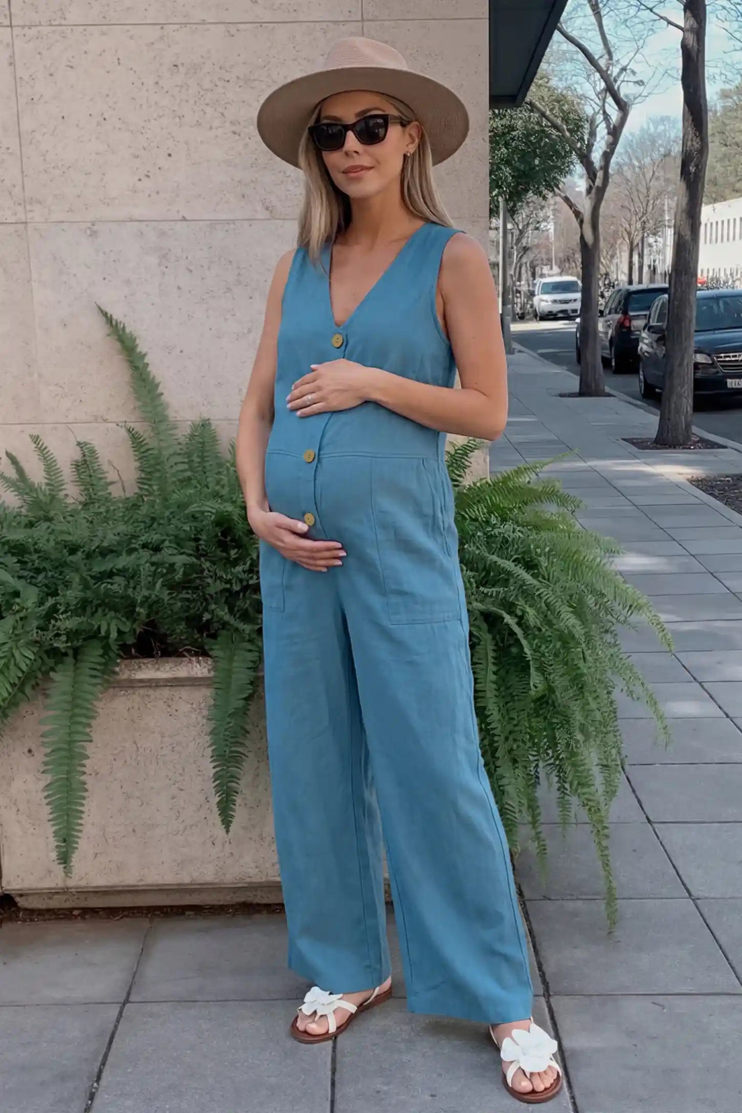 Wide-Leg V-Neck Button-Front Maternity Jumpsuit Wide-leg V-neck button-front maternity jumpsuit in blue with sleeveless V-neckline and button-front detail, front view on pregnant model