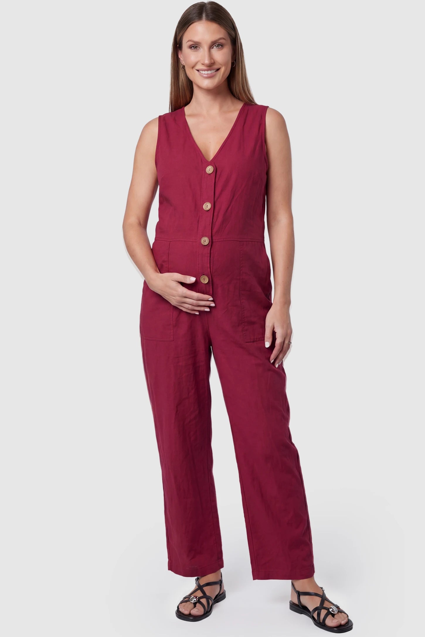Wide-Leg V-Neck Button-Front Maternity Jumpsuit Wide-leg V-neck button-front maternity jumpsuit in wine red with sleeveless V-neckline and button-front detail, front view on pregnant model