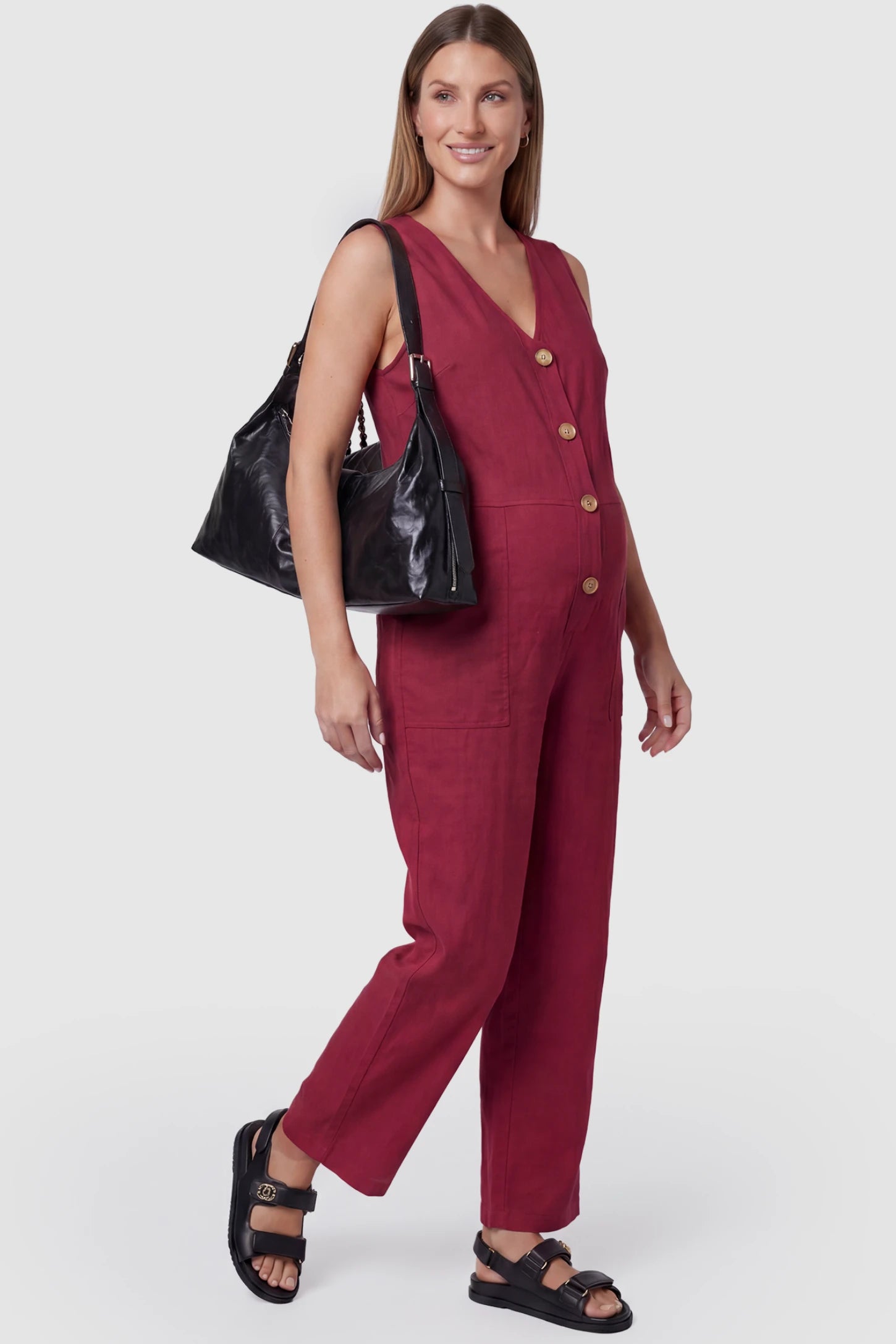 Wide-Leg V-Neck Button-Front Maternity Jumpsuit Wide-leg V-neck button-front maternity jumpsuit in wine red with sleeveless V-neckline and button-front detail, front view on pregnant model
