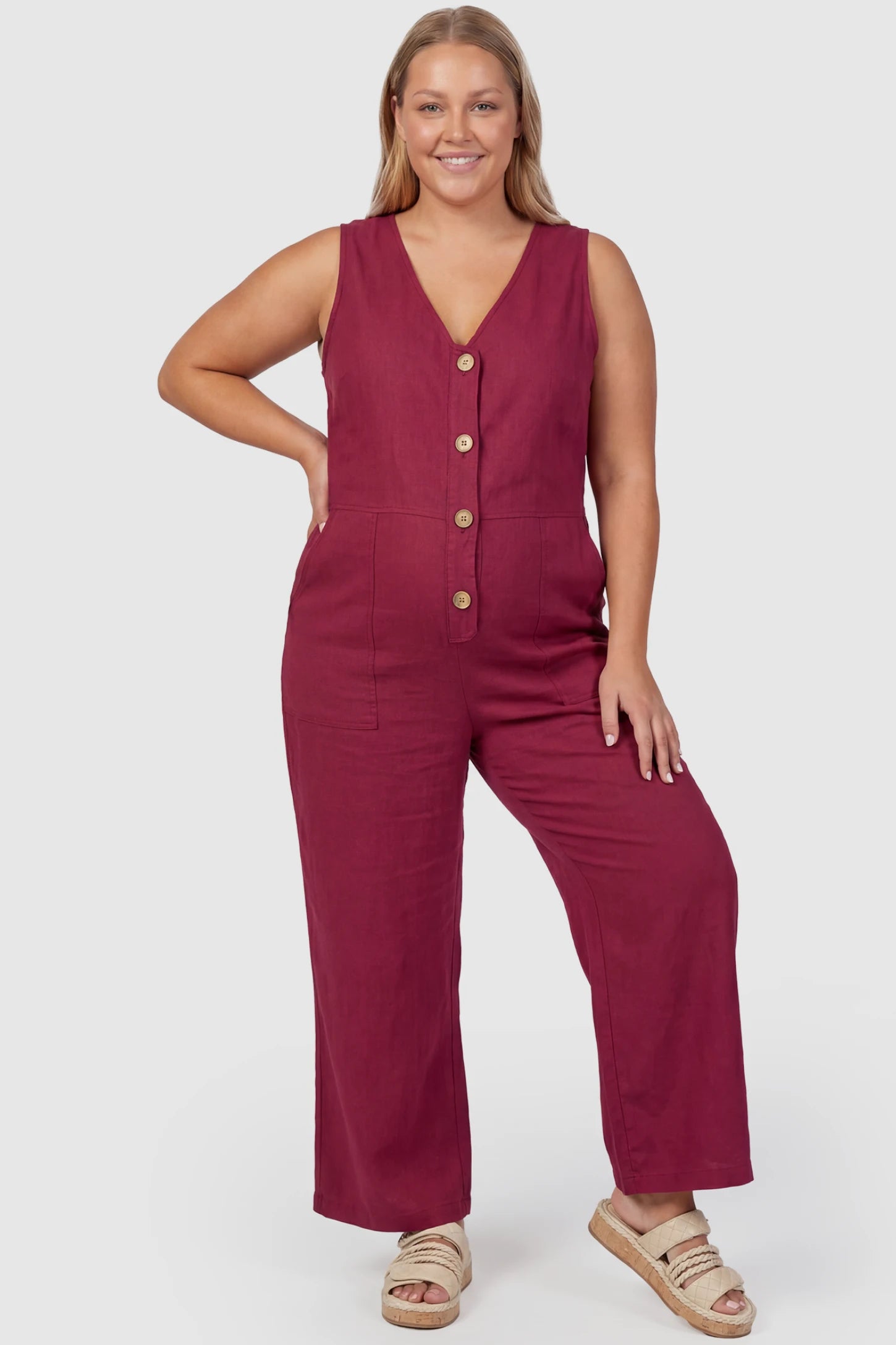 Wide-Leg V-Neck Button-Front Maternity Jumpsuit Wide-leg V-neck button-front maternity jumpsuit in wine red with sleeveless V-neckline and button-front detail, front view on plus-size model