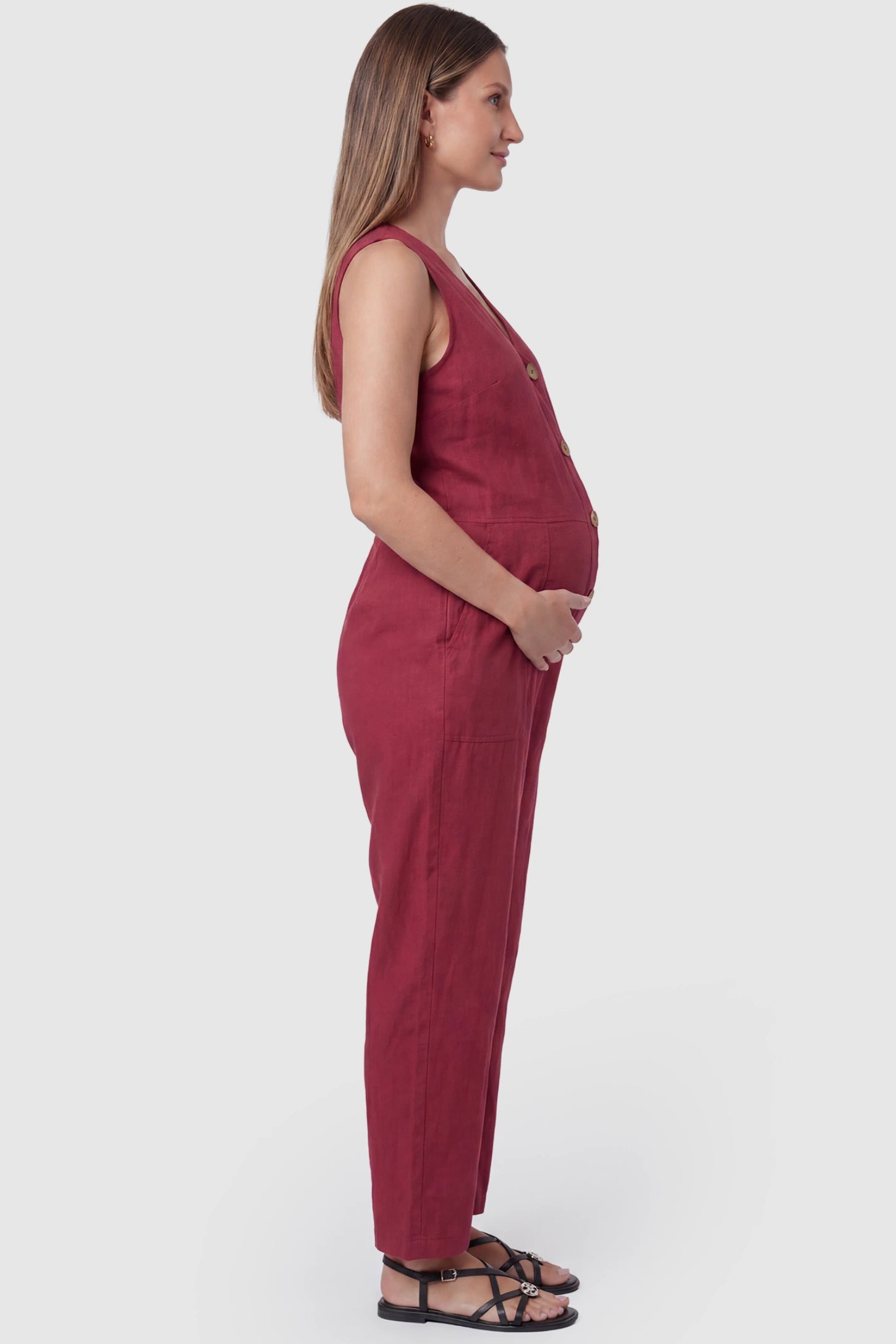 Wide-Leg V-Neck Button-Front Maternity Jumpsuit Wide-leg V-neck button-front maternity jumpsuit in wine red with sleeveless cut, side view on pregnant model