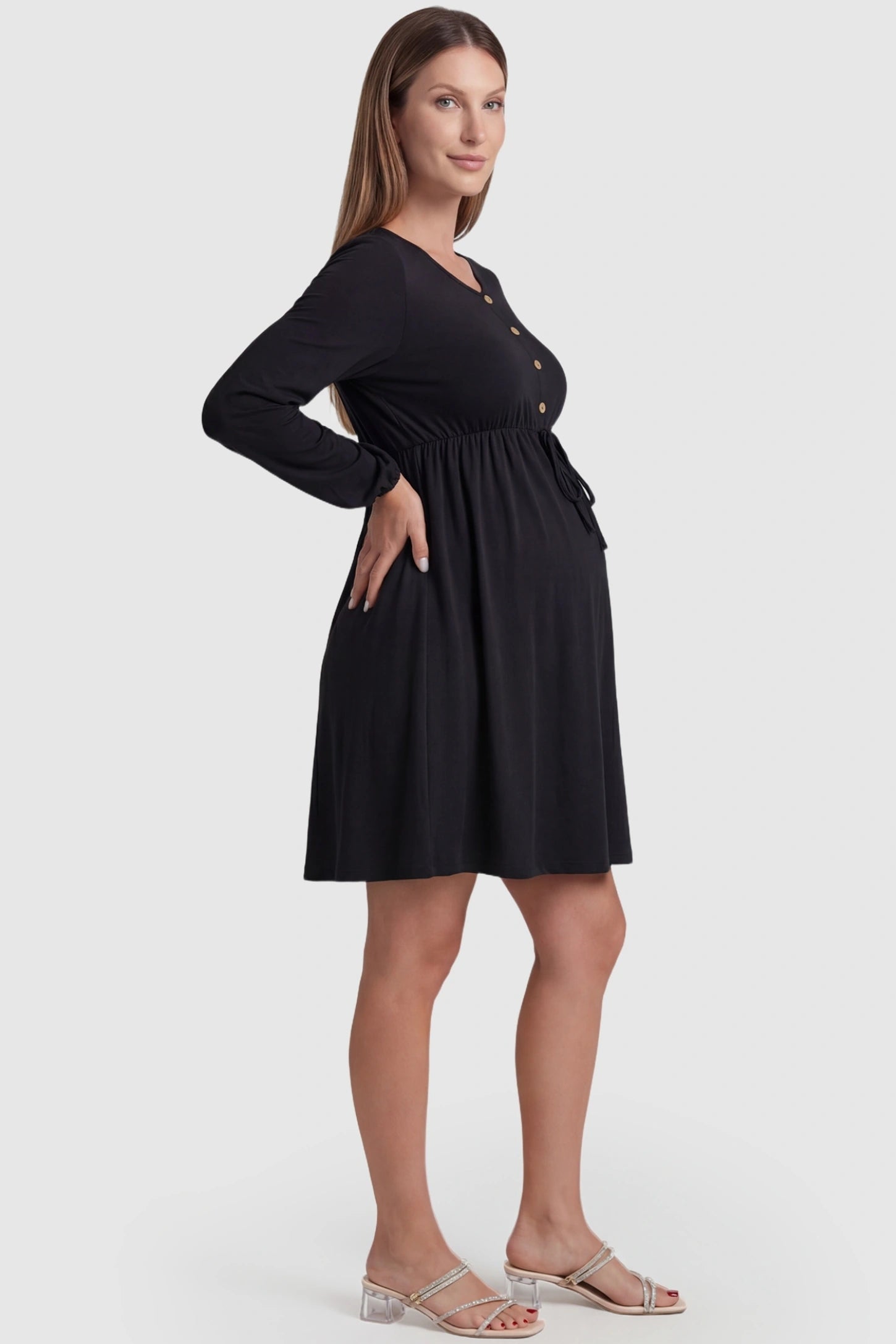 Button-Front Drawstring Waist Maternity Mini Dress Button-Front Drawstring Waist Maternity Mini Dress in Black featuring a stretchy A-line skirt on a pregnant model, side view.