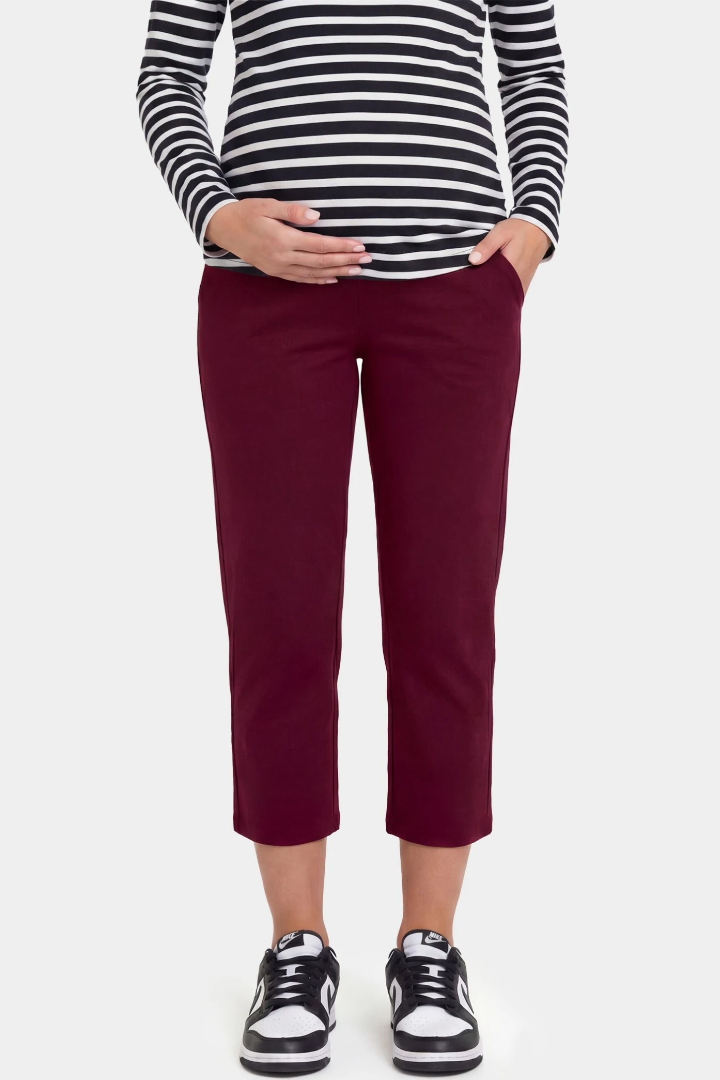 High-Waist Belly Support Loose-Fit Capri Maternity Pants High-waist belly support loose-fit capri maternity pants in burgundy with functional side pockets, front view on pregnant model