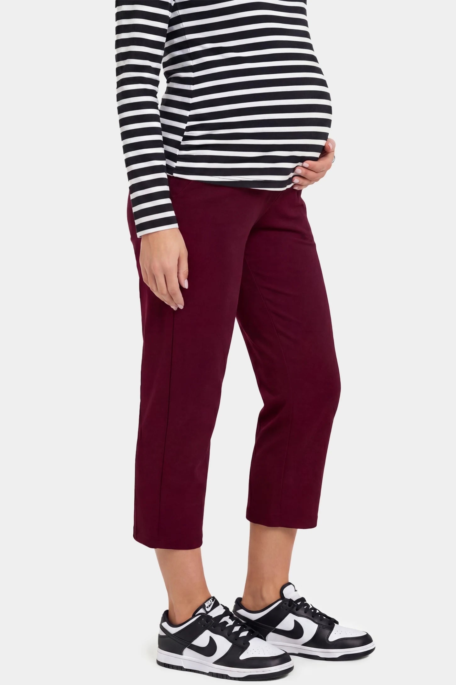 High-Waist Belly Support Loose-Fit Capri Maternity Pants High-waist belly support loose-fit capri maternity pants in burgundy with cropped length, side view on pregnant model