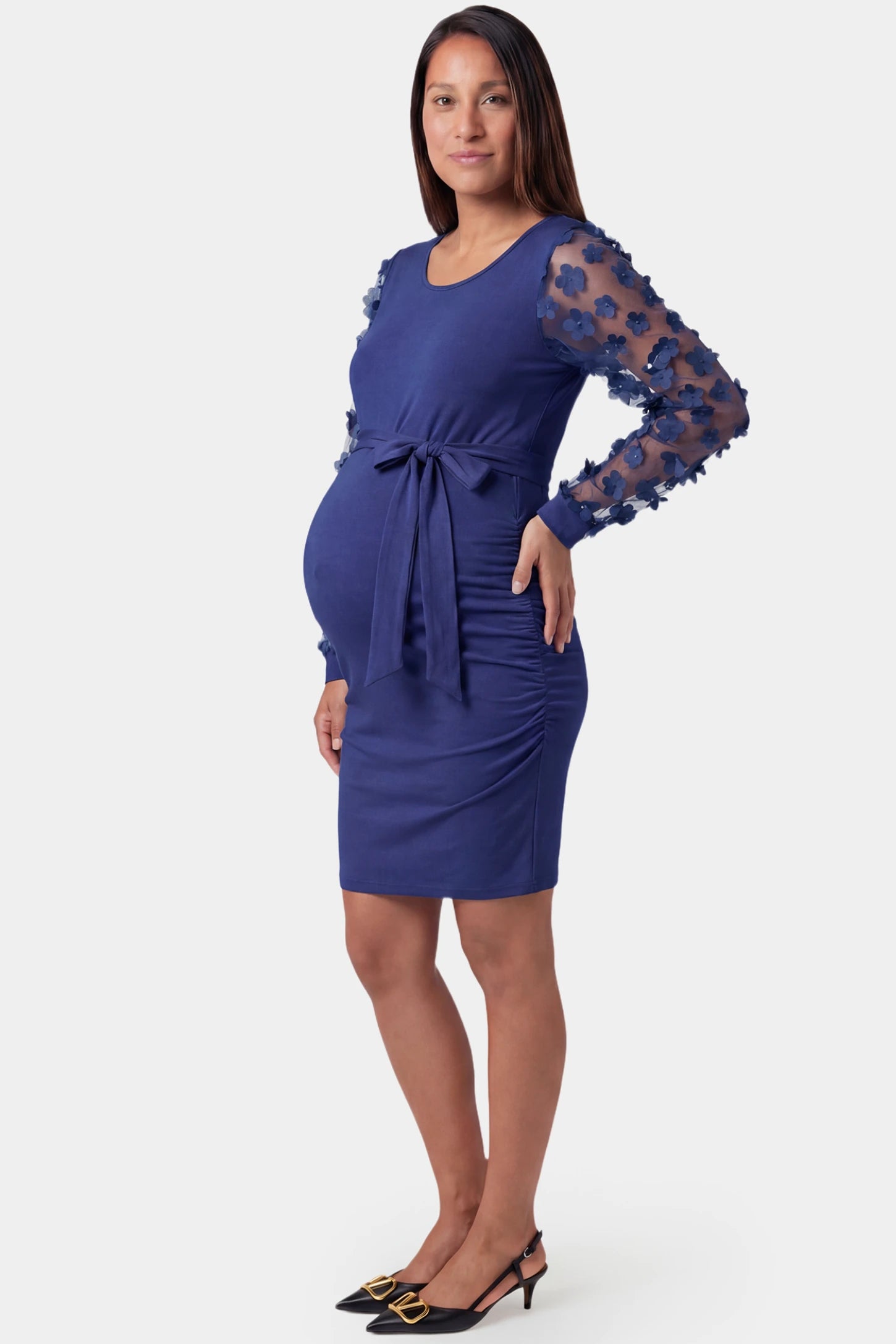 Sheer Long-Sleeve Tie-Waist Short Maternity Dress Sheer long-sleeve tie-waist short maternity dress in dark blue featuring side ruching detail in side view on a pregnant model
