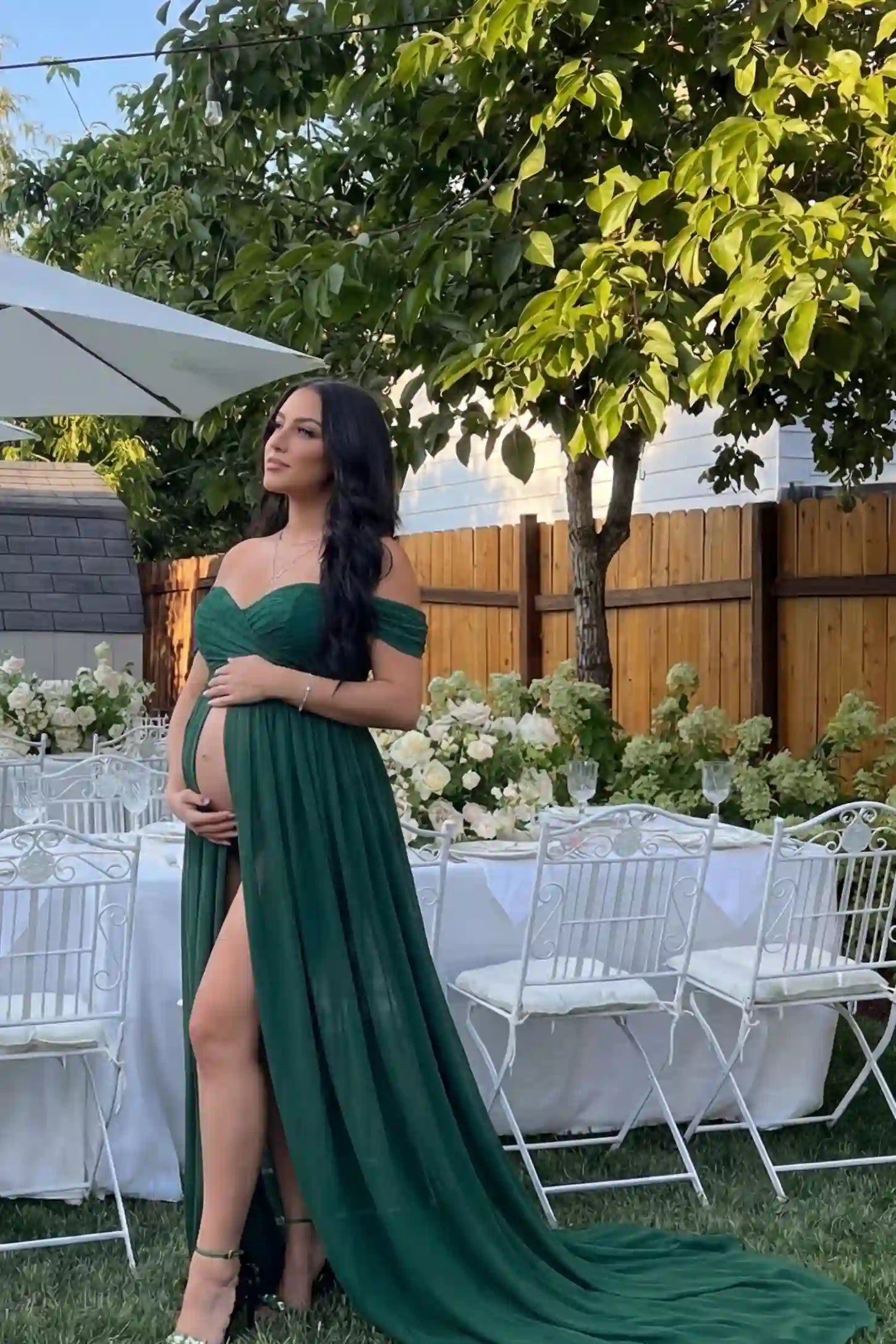 Chiffon Split-Front Maxi Maternity Photoshoot Gown Chiffon Split-Front Maxi Maternity Photoshoot Dress in Green featuring off-the-shoulder sleeves on a pregnant model in a garden.