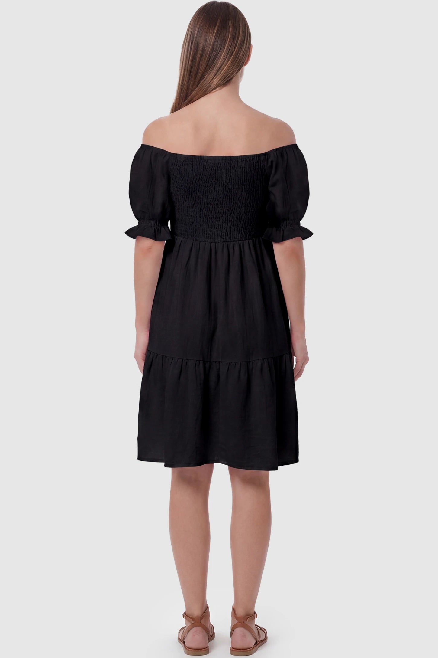 Smocked Off-Shoulder Empire Waist Maternity Short Dress Smocked off-shoulder empire waist maternity short dress in black with short puff sleeve, back view on pregnant model