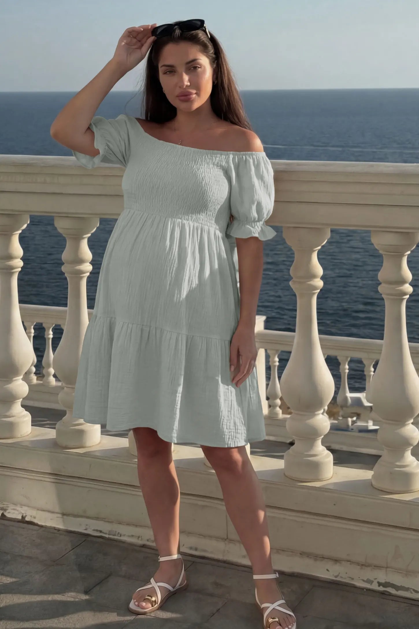 Smocked Off-Shoulder Empire Waist Maternity Short Dress Smocked off-shoulder empire waist maternity short dress in light green with smocked bodice detail, front view on pregnant model
