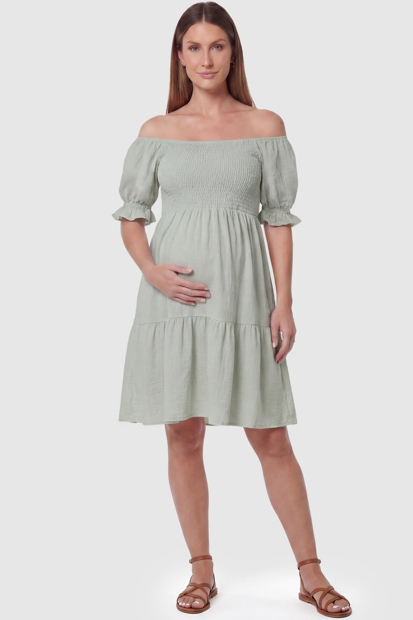 Smocked Off-Shoulder Empire Waist Maternity Short Dress Smocked off-shoulder empire waist maternity short dress in light green with smocked bodice detail, front view on pregnant model